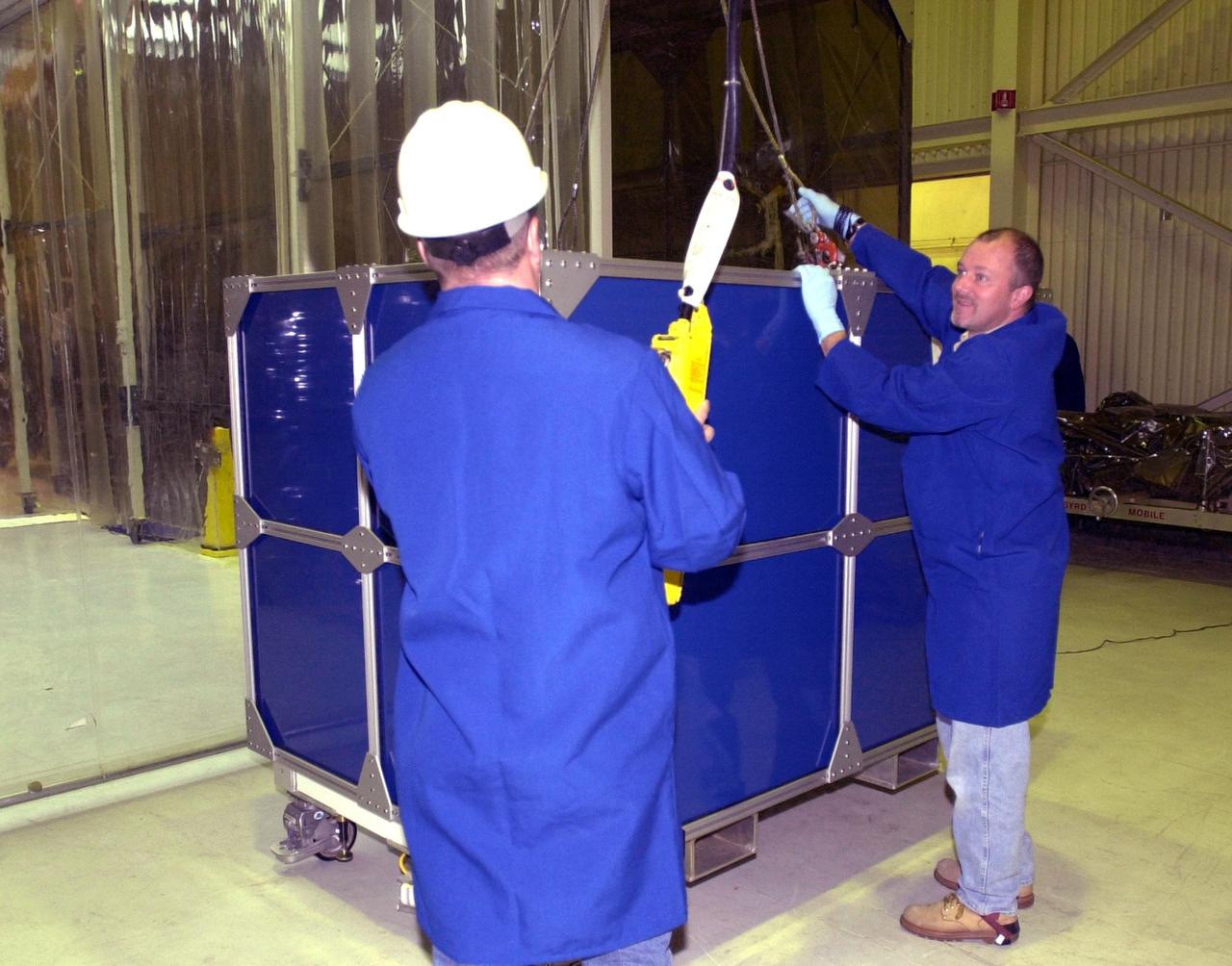 VANDENBERG AIR FORCE BASE, Calif.  —  Inside Orbital Sciences’ Building 1555 at Vandenberg Air Force Base in California, workers attach the wires to lift the shipping container surrounding the Space Technology 5 (ST5) spacecraft.  ST5 will be launched by a Pegasus XL rocket. The satellites contain miniaturized redundant components and technologies.  Each will validate New Millennium Program selected technologies, such as the Cold Gas Micro-Thruster and X-Band Transponder Communication System.  After deployment from the Pegasus, the micro-satellites will be positioned in a “string of pearls” constellation that demonstrates the ability to position them to perform simultaneous multi-point measurements of the magnetic field using highly sensitive magnetometers.  The data will help scientists understand and map the intensity and direction of the Earth’s magnetic field, its relation to space weather events, and affects on our planet.  With such missions, NASA hopes to improve scientists’ ability to accurately forecast space weather and minimize its harmful effects on space- and ground-based systems.  Launch of ST5 is scheduled for Feb. 28 from Vandenberg Air Force Base.