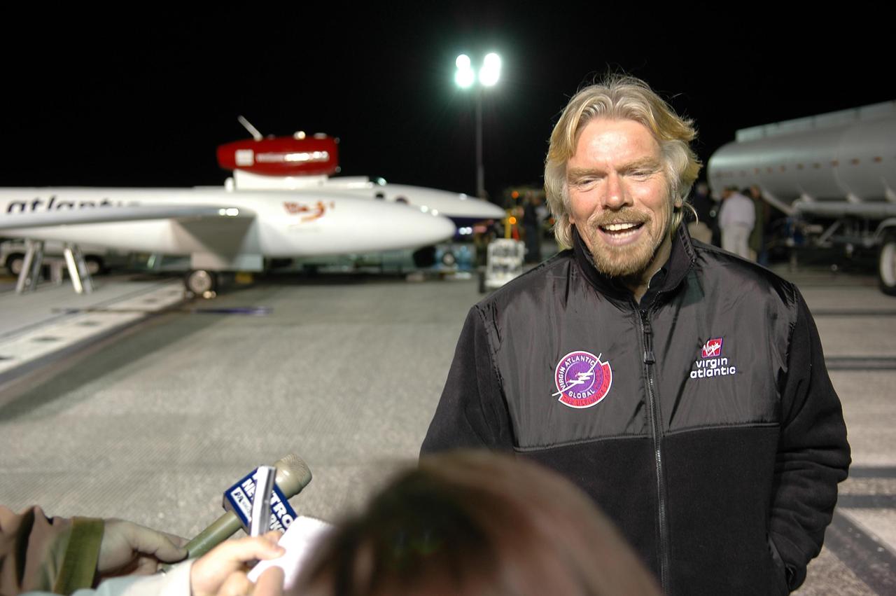 KENNEDY SPACE CENTER, FLA. -    During fueling of the Virgin Atlantic GlobalFlyer before dawn on NASA Kennedy Space Center’s Shuttle Landing Facility (SLF), Sir Richard Branson talks to the media.  Branson is chairman and founder of Virgin Atlantic. The GlobalFlyer is in the background. Steve Fossett will pilot the GlobalFlyer on a record-breaking attempt by flying solo, non-stop without refueling, to surpass the current record for the longest flight of any aircraft.  Fossett is expected to take off from the KSC SLF.  Later, takeoff of the GlobalFlyer was postponed due to a fuel leak that appeared during the last moments of loading. The next planned takeoff attempt is 7 a.m. Feb. 8 from the SLF.   Photo credit: NASA/Kim Shiflett