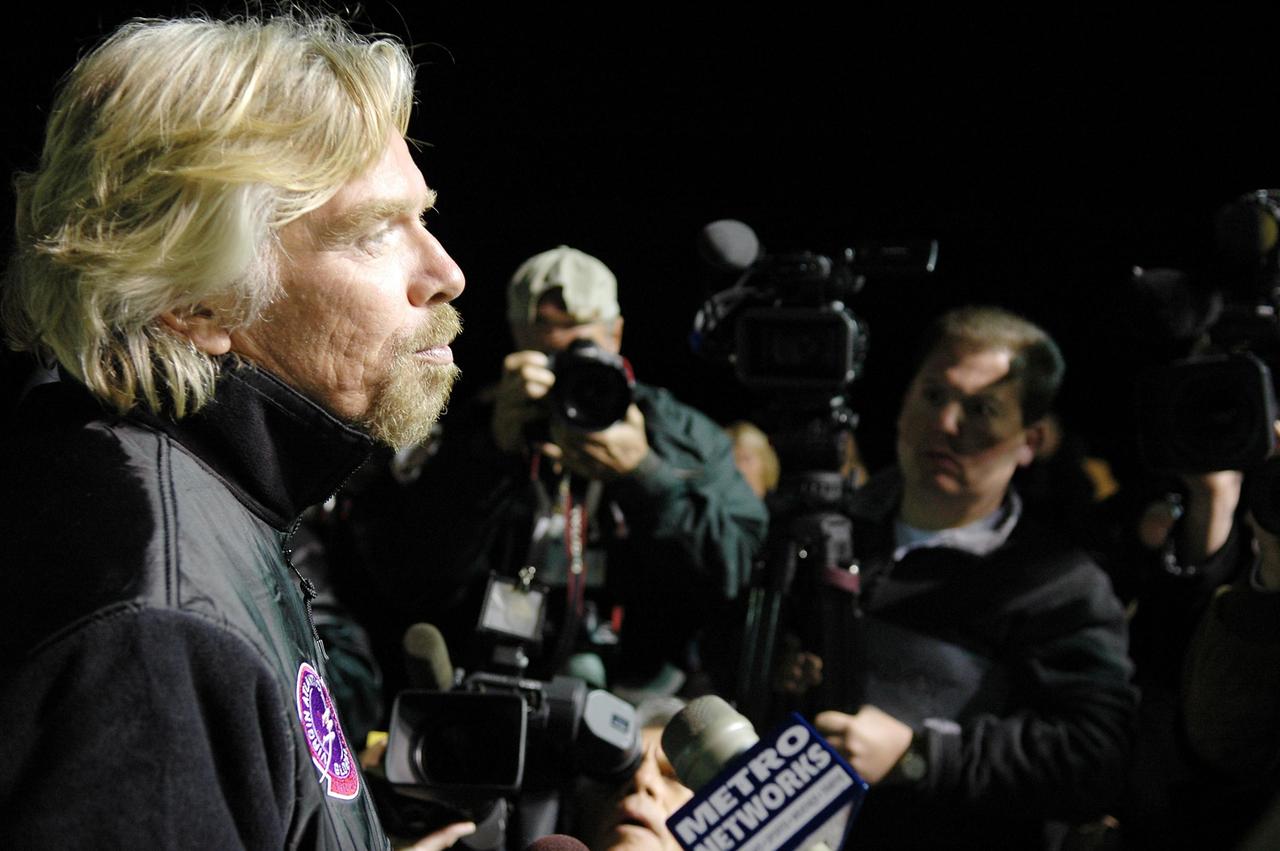 KENNEDY SPACE CENTER, FLA. -    Before dawn on NASA Kennedy Space Center’s Shuttle Landing Facility (SLF), Sir Richard Branson talks to the media.  Branson is chairman and founder of Virgin Atlantic, which is sponsoring the GlobalFlyer. Steve Fossett will pilot the GlobalFlyer on a record-breaking attempt by flying solo, non-stop without refueling, to surpass the current record for the longest flight of any aircraft.  Fossett is expected to take off from the KSC SLF.  Later, takeoff of the GlobalFlyer was postponed due to a fuel leak that appeared during the last moments of loading. The next planned takeoff attempt is 7 a.m. Feb. 8 from the SLF.   Photo credit: NASA/Kim Shiflett