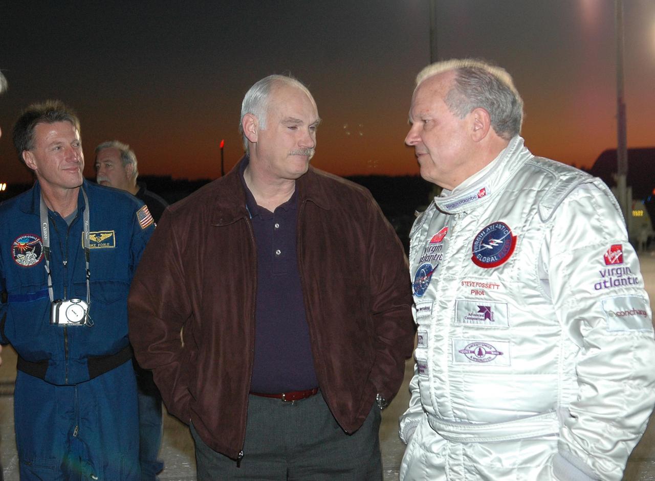 KENNEDY SPACE CENTER, FLA. -   As a rosy dawn creeps over the horizon, Deputy Associate Administrator for Exploration Operations Michael Foale (left) and astronaut Bill Readdy (center) talk to Steve Fossett about the anticipated flight of the Virgin Atlantic GlobalFlyer. Fossett will pilot the GlobalFlyer on a record-breaking attempt by flying solo, non-stop without refueling, to surpass the current record for the longest flight of any aircraft.  Fossett is expected to take off from the KSC SLF.  Later, takeoff of the GlobalFlyer was postponed due to a fuel leak that appeared during the last moments of loading. The next planned takeoff attempt is 7 a.m. Feb. 8 from the SLF.   Photo credit: NASA/Kim Shiflett