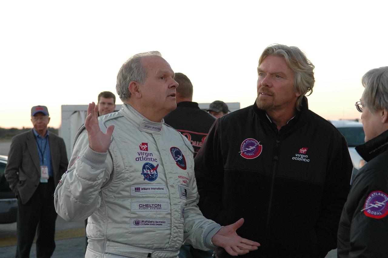 KENNEDY SPACE CENTER, FLA. -   Pilot Steve Fossett (left) and Sir Richard Branson (right) talk with Virgin Atlantic GlobalFlyer team members about the fuel leak detected in the aircraft.   Branson is chairman and founder of Virgin Atlantic.  Fossett will pilot the GlobalFlyer on a record-breaking attempt by flying solo, non-stop without refueling, to surpass the current record for the longest flight of any aircraft.  Fossett was expected to take off from the KSC SLF before the takeoff was postponed due to the fuel leak that appeared in the last moments of loading. The next planned takeoff attempt is 7 a.m. Feb. 8 from the SLF.   Photo credit: NASA/Kim Shiflett