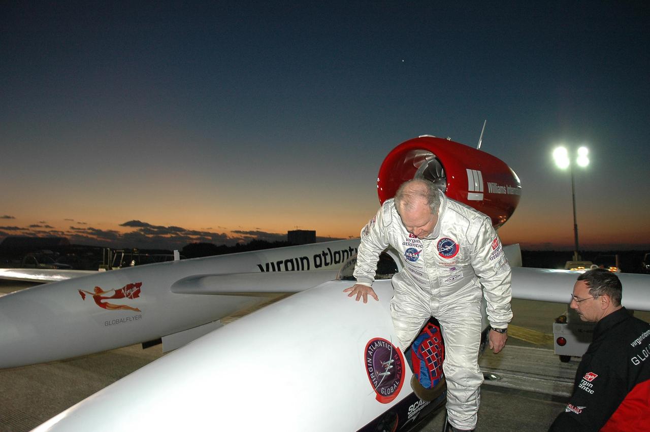 KENNEDY SPACE CENTER, FLA. -   Just at dawn, Steve Fossett (left) climbs into the Virgin Atlantic GlobalFlyer parked on NASA Kennedy Space Center’s Shuttle Landing Facility.  Fossett will pilot the GlobalFlyer on a record-breaking attempt by flying solo, non-stop without refueling, to surpass the current record for the longest flight of any aircraft. This is the second attempt in two days after a fuel leak was detected Feb. 7.  The expected time of takeoff is 7 a.m.  Photo credit: NASA/Kim Shiflett