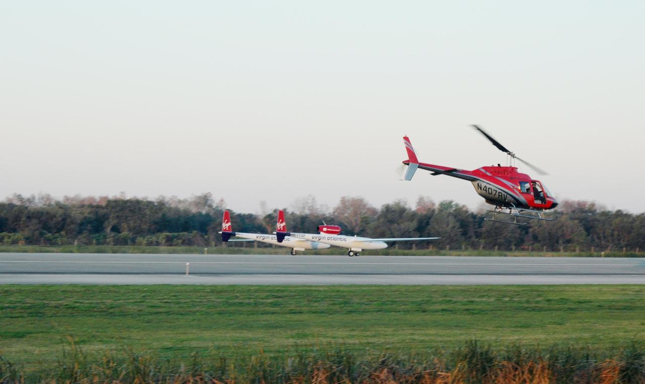 KENNEDY SPACE CENTER, FLA. -   On NASA Kennedy Space Center’s Shuttle Landing Facility runway, the Virgin Atlantic GlobalFlyer, piloted by Steve Fossett, begins its takeoff as a nearby helicopter films the historic event for audiences in the United Kingdom.  Fossett is attempting a record-breaking solo flight, non-stop without refueling, to surpass the current record for the longest flight of any aircraft. This is the second attempt in two days after a fuel leak was detected Feb. 7.  The actual launch time was 7:22 a.m. Feb. 8.