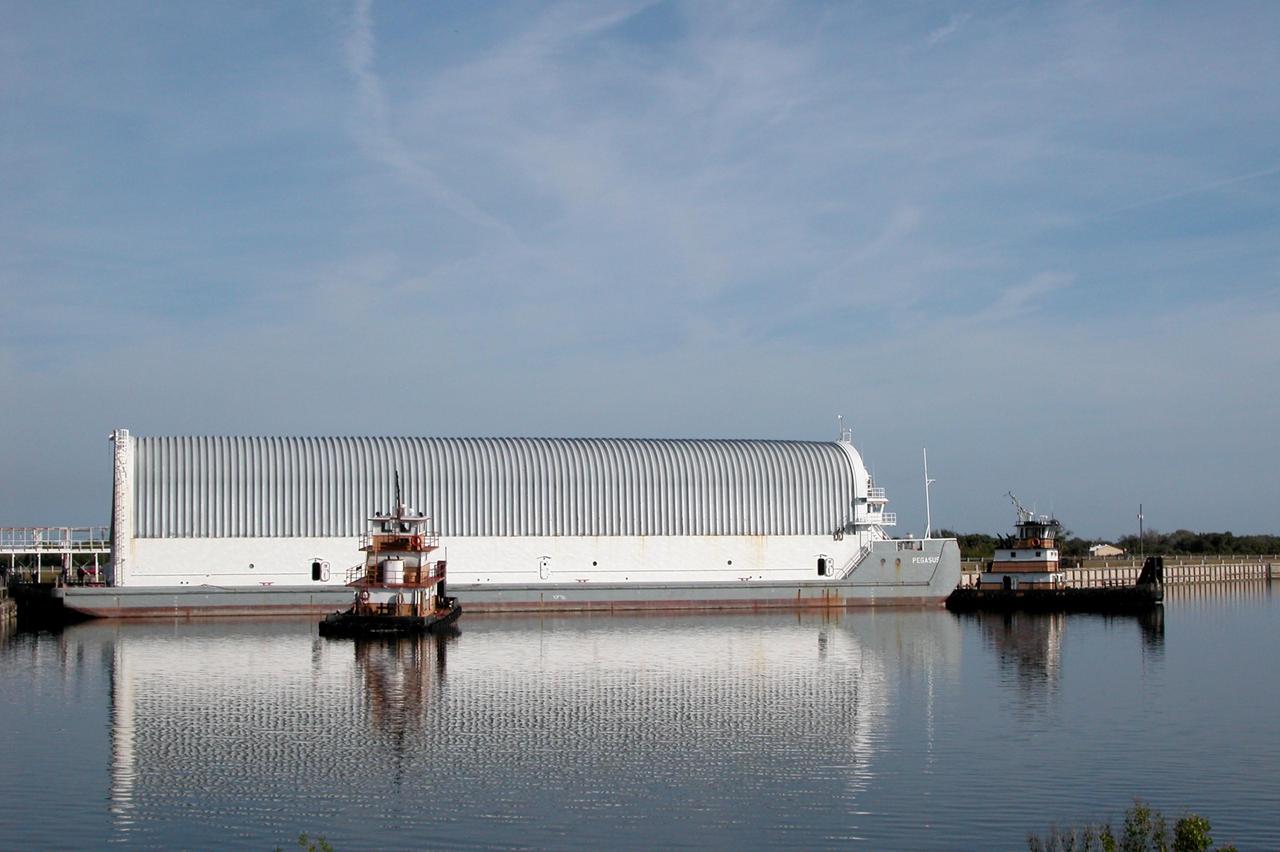 KENNEDY SPACE CENTER, FLA. - A tugboat slides into place next to the Pegasus barge in the Turn Basin to move it into the channel on its way to Port Canaveral. The Pegasus is leaving NASA Kennedy Space Center for the Michoud Assembly Plant in Mississippi to get the external tank for the next shuttle mission, STS-121. To make the round trip from the port, the barge is towed by one of the solid rocket booster retrieval ships. The tank has been undergoing inspection and maintenance at the assembly plant. Space Shuttle Discovery is scheduled to launch in May. Photo credit: NASA/Debbie Kiger