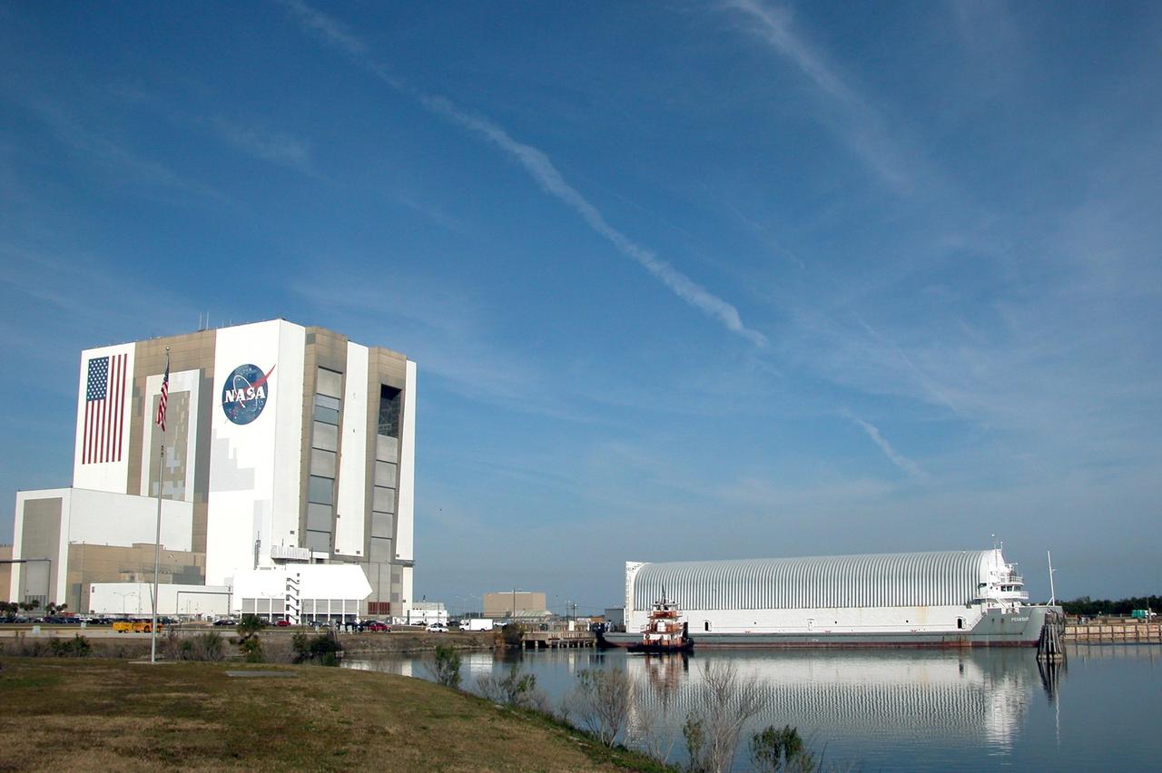 KENNEDY SPACE CENTER, FLA. - A tugboat slides into place next to the Pegasus barge in the Turn Basin, located near the Vehicle Assembly Building (at left) to move it into the channel on its way to Port Canaveral. The Pegasus is leaving NASA Kennedy Space Center for the Michoud Assembly Plant in Mississippi to get the external tank for the next shuttle mission, STS-121. To make the round trip from the port, the barge is towed by one of the solid rocket booster retrieval ships. The tank has been undergoing inspection and maintenance at the assembly plant. Space Shuttle Discovery is scheduled to launch in May. Photo credit: NASA/Debbie Kiger