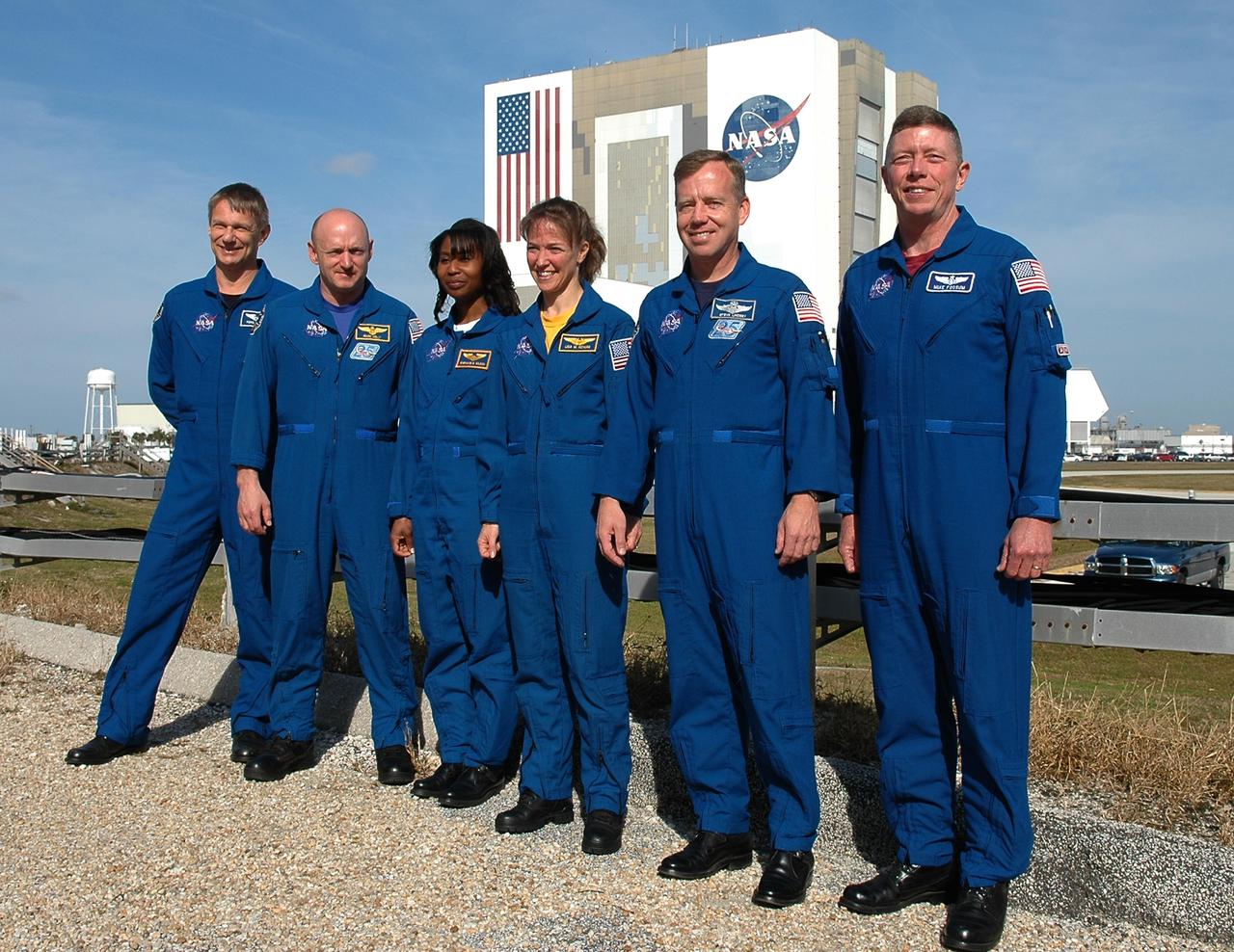 KENNEDY SPACE CENTER, FLA. -  The STS-121 crew stands for a photo in front of the Vehicle Assembly Building after a media conference. From left are Mission Specialist Piers Sellers, Pilot Mark Kelly, Mission Specialists Stephanie Wilson and Lisa Nowak, Commander Steven Lindsey and Mission Specialist Michael Fossum.  The remaining member of the crew, not pictured, is Mission Specialist Thomas Reiter.  The crew is at NASA Kennedy Space Center for the crew equipment interface test, which provides hands-on experiences with equipment used on-orbit. The launch of STS-121, the second return-to-flight mission, is scheduled for May.   Photo credit: NASA/Kim Shiflett
