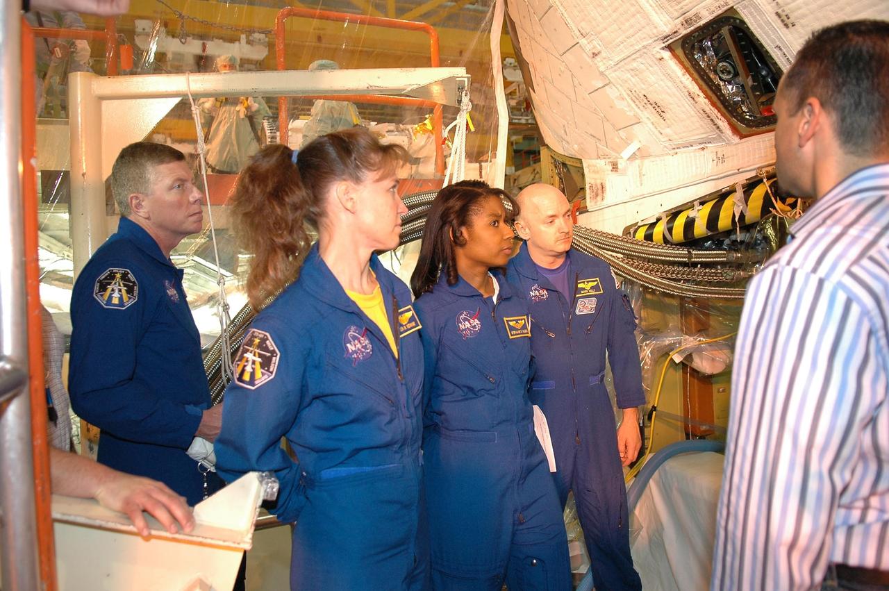 KENNEDY SPACE CENTER, FLA. -  Inside the Orbiter Processing Facility bay 3 at NASA's Kennedy Space Center, members of the STS-121 crew look at Discovery, the launch vehicle for the mission. From left are Mission Specialists Michael Fossum, Lisa Nowak and Stephanie Wilson, and Pilot Mark Kelly. The crew is at Kennedy to take part in the crew equipment interface test (CEIT), which provides hands-on experience with equipment they will use on orbit.  Launch of STS-121, the second return-to-flight mission, is scheduled for no earlier than May.  Photo credit: NASA/Kim Shiflett