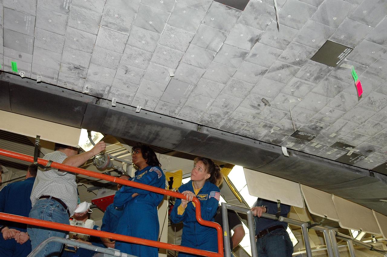 KENNEDY SPACE CENTER, FLA. - Inside the Orbiter Processing Facility bay 3 at NASA's Kennedy Space Center, STS-121 Mission Specialists Stephanie Wilson (left) and Lisa Nowak learn from technicians the work that has been done on Discovery, the launch vehicle for the mission.  They and other crew members -- Commander Steven Lindsey, Pilot Mark Kelly and Mission Specialists Michael Fossum and Piers Sellers -- are at Kennedy for a crew equipment interface test, which provides hands-on experience with equipment they will use on orbit.   Launch of STS-121, the second return-to-flight mission, is scheduled for no earlier than May.  Photo credit: NASA/Kim Shiflett