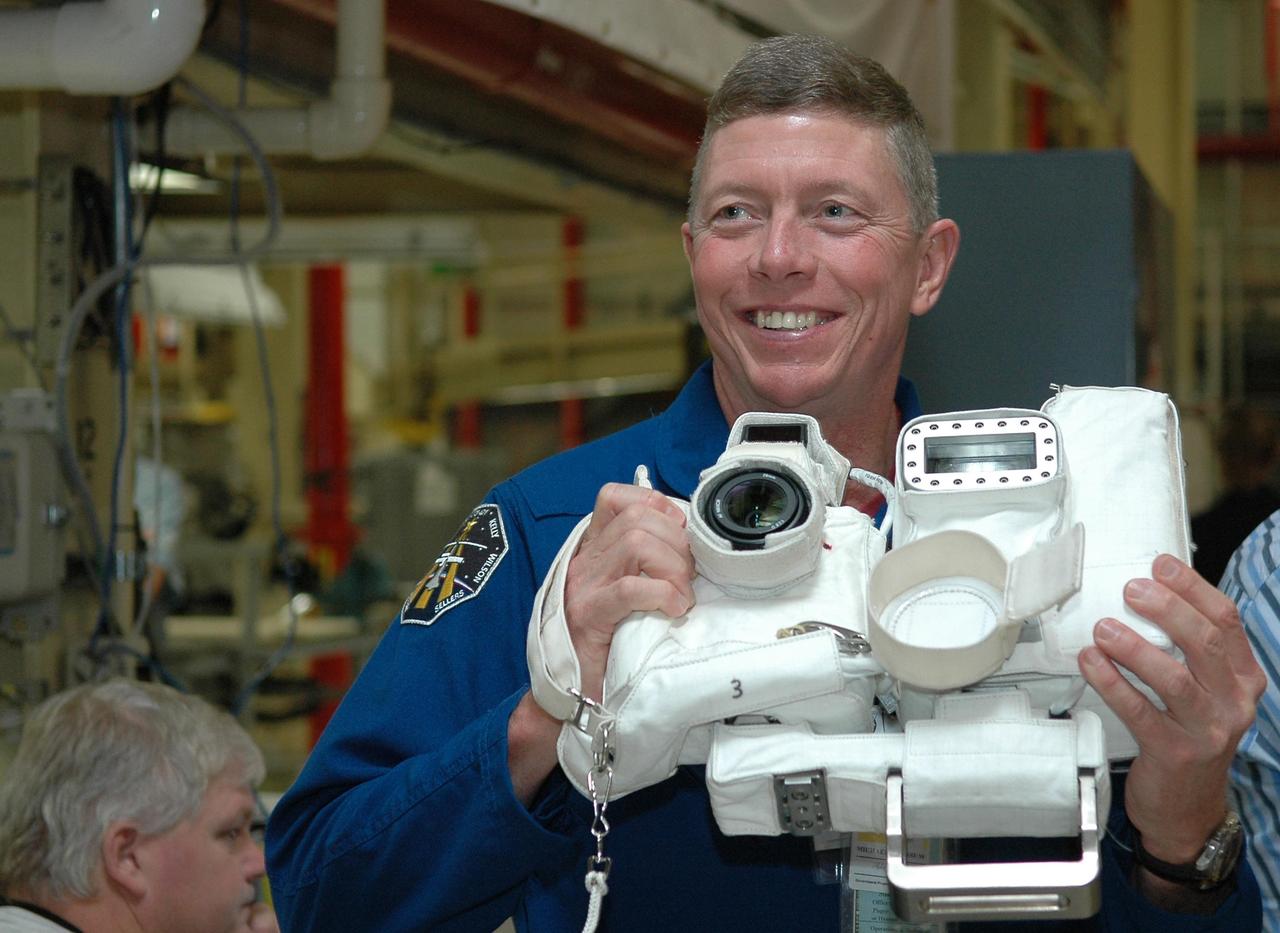 KENNEDY SPACE CENTER, FLA. - Inside the Orbiter Processing Facility bay 3 at NASA's Kennedy Space Center, STS-121 Mission Specialist Michael Fossum handles a working prototype of a camera that will be used on the mission.  He and other crew members -- Commander Steven Lindsey, Pilot Mark Kelly and Mission Specialists Lisa Nowak, Stephanie Wilson and Piers Sellers -- are at Kennedy for a crew equipment interface test, which provides hands-on experience with equipment they will use on orbit. Launch of STS-121, the second return-to-flight mission, is scheduled for no earlier than May.  Photo credit: NASA/Kim Shiflett