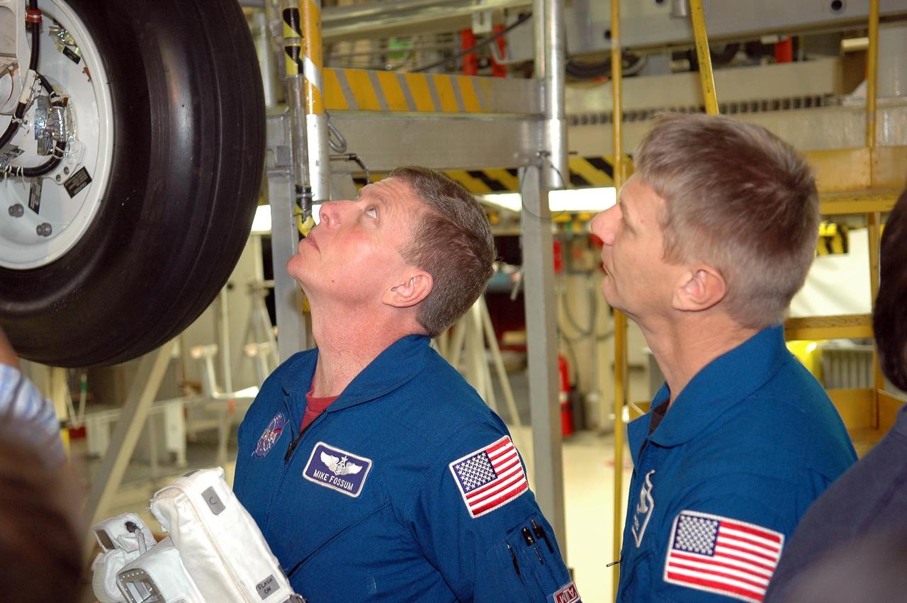 KENNEDY SPACE CENTER, FLA. -  Inside the Orbiter Processing Facility bay 3 at NASA's Kennedy Space Center, members of the STS-121 crew take a close look at the wheels on Discovery, the launch vehicle for the mission. From left are Mission Specialists Michael Fossum and Piers Sellers.  The crew is at Kennedy for the crew equipment interface test, which provides hands-on experience with equipment they will use on orbit.  Launch of STS-121, the second return-to-flight mission, is scheduled for no earlier than May.  Photo credit: NASA/Kim Shiflett