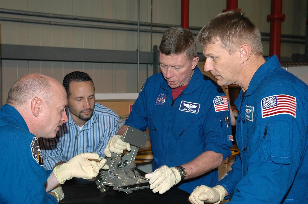 KENNEDY SPACE CENTER, FLA. - In NASA Kennedy Space Center's Orbiter Processing Facility bay 3, members of the STS-121 crew practice working with hardware for the mission under the watchful eyes of Tomas Gonzalez-Torres, with NASA's Johnson Space Center. At left is Pilot Mark Kelly; at right are Mission Specialists Michael Fossum and Piers Sellers. The crew is at Kennedy to take part in the crew equipment interface test, which provides hands-on experience with equipment to be used on-orbit. Launch of Space Shuttle Discovery on mission STS-121, the second return-to-flight mission, is scheduled no earlier than May.