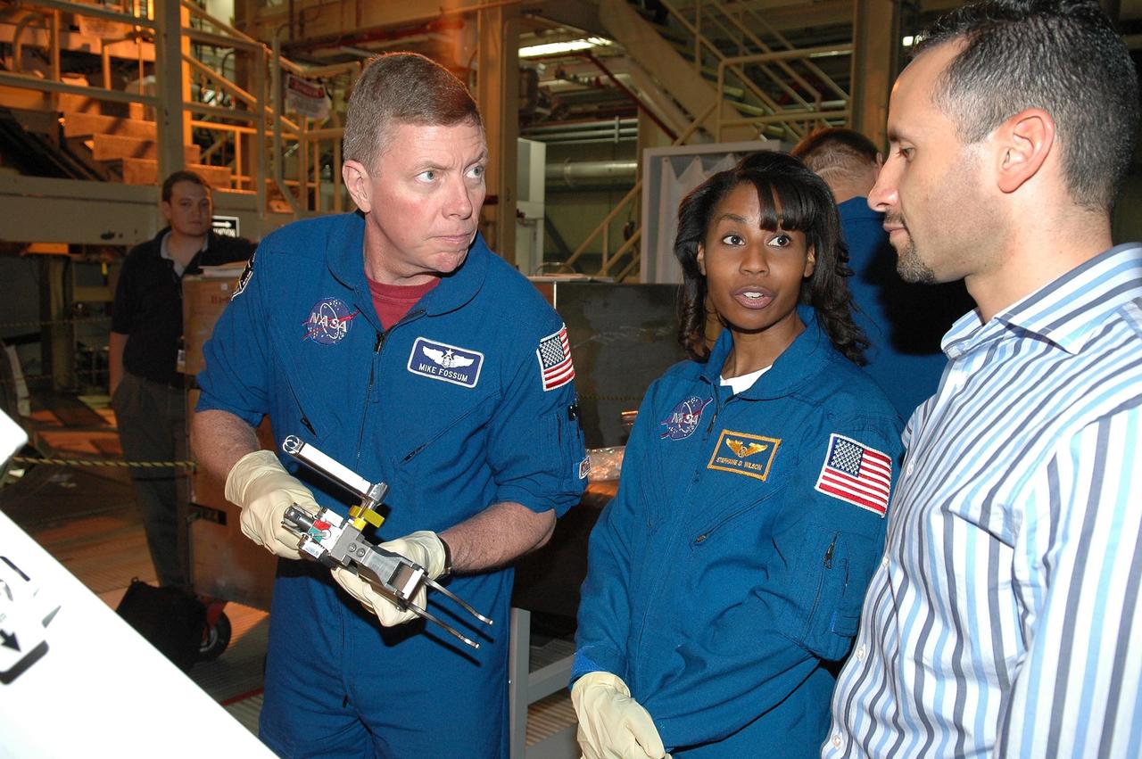 KENNEDY SPACE CENTER, FLA. - In NASA Kennedy Space Center's Orbiter Processing Facility bay 3, STS-121 Mission Specialist Michael Fossum (left) talks to Tomas Gonzalez-Torres, with NASA's Johnson Space Center, about the equipment he is handling. Next to Fossum is Mission Specialist Stephanie Wilson. The crew is at Kennedy to take part in the crew equipment interface test, which provides hands-on experience with equipment to be used on-orbit. Launch of Space Shuttle Discovery on mission STS-121, the second return-to-flight mission, is scheduled no earlier than May.