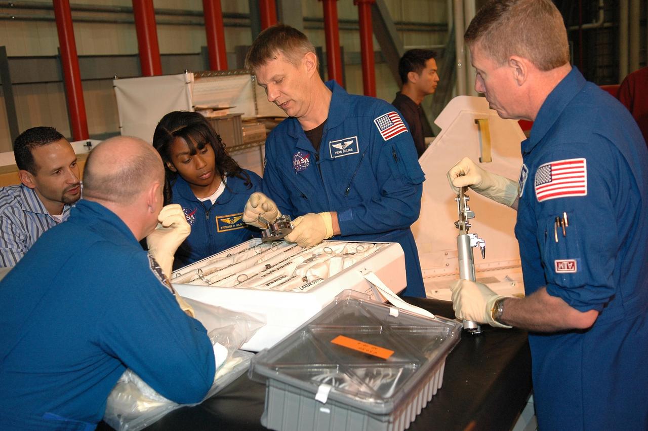 KENNEDY SPACE CENTER, FLA. - In NASA Kennedy Space Center's Orbiter Processing Facility bay 3, members of the STS-121 crew practice working with equipment for the mission. From the left are Tomas Gonzalez-Torres, with NASA's Johnson Space Center; then Mission Specialists Stephanie Wilson, Piers Sellers and Michael Fossum.  Pilot Mark Kelly has his back to the camera.  The crew is at Kennedy to take part in the crew equipment interface test, which provides hands-on experience with equipment to be used on-orbit. Launch of Space Shuttle Discovery on mission STS-121, the second return-to-flight mission, is scheduled no earlier than May.