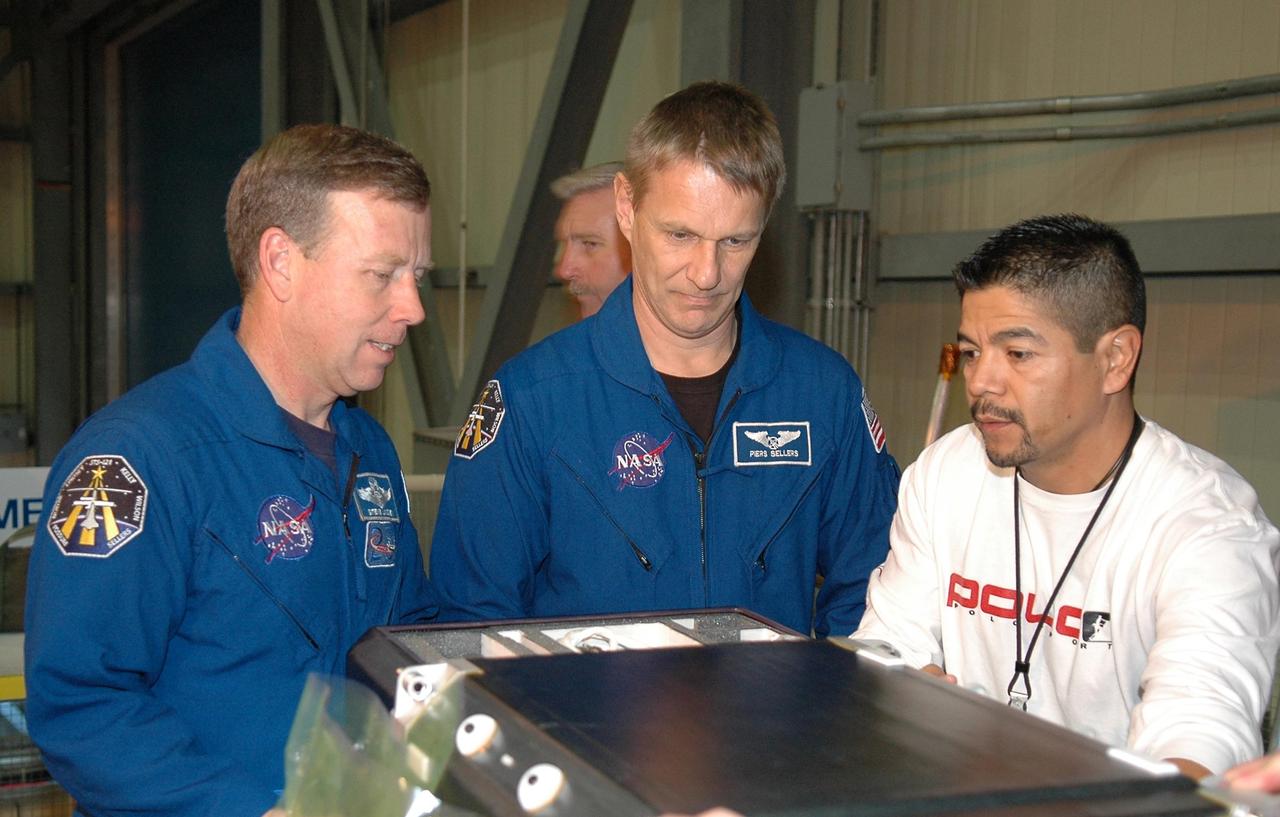 KENNEDY SPACE CENTER, FLA. - In NASA Kennedy Space Center's Orbiter Processing Facility bay 3, STS-121 Commander Steve Lindsey and Mission Specialist Piers Sellers, under the watchful eyes of Victor Badillo, practice working with equipment for the mission.  Badillo, with United Space Alliance, is a flight maintenance trainer from Johnson Space Center.  The crew is at Kennedy to take part in the crew equipment interface test, which provides hands-on experience with equipment to be used on-orbit. Launch of Space Shuttle Discovery on mission STS-121, the second return-to-flight mission, is scheduled no earlier than May.