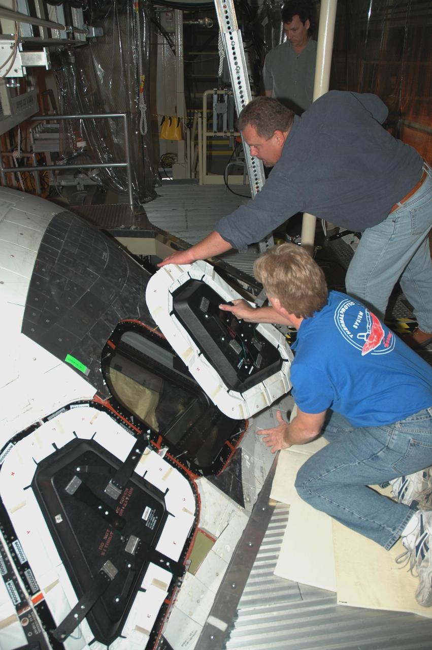 KENNEDY SPACE CENTER, FLA.  - In NASA Kennedy Space Center's Orbiter Processing Facility bay 3, United Space Alliance shuttle technicians remove the hard cover from a window on Space Shuttle Discovery to enable STS-121 crew members to inspect the window from the cockpit.  Launch of Space Shuttle Discovery on mission STS-121, the second return-to-flight mission, is scheduled no earlier than May.