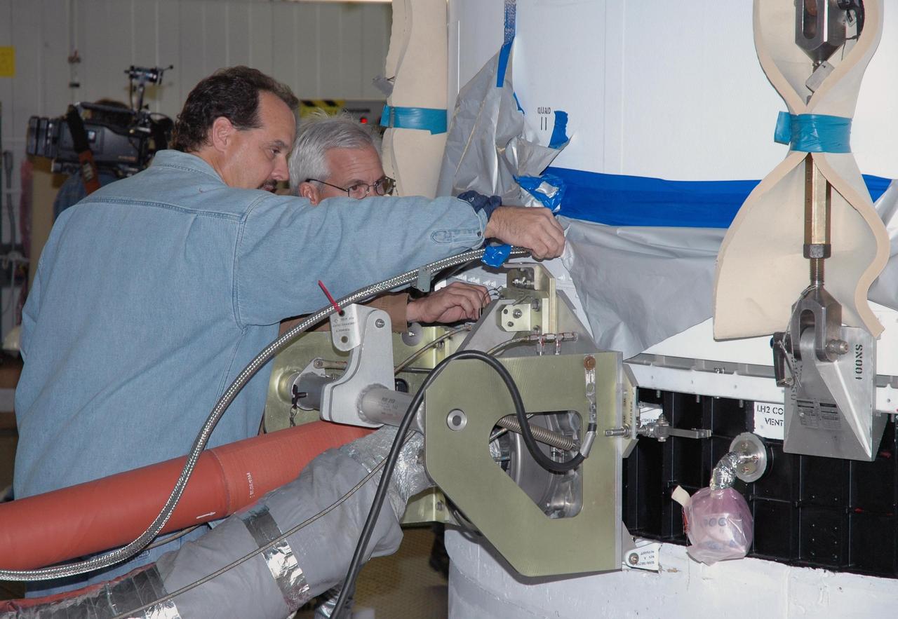 KENNEDY SPACE CENTER, FLA. - On Launch Complex 37 at Cape Canaveral Air Force Station in Florida, technicians disconnect fittings on the GOES-N satellite before it is demated from its Boeing Delta IV rocket. Launch of the satellite was postponed in August 2005 due to technical issues and postponed to a later date. Due to the extended length of time the spacecraft has been atop the rocket without launching, the weather satellite is being returned to the Astrotech Space Operations payload processing facility for some precautionary retesting and state-of-health checks. GOES-N is the latest in a series of Geostationary Operational Environmental Satellites for NOAA and NASA providing continuous monitoring necessary for intensive data analysis.  Photo credit: NASA/Jim Grossmann