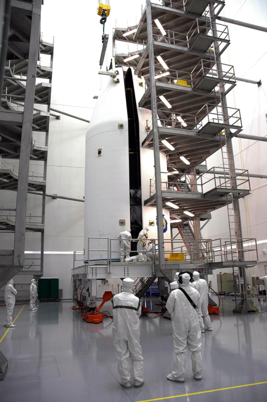 KENNEDY SPACE CENTER, FLA. - At Astrotech Space Operations payload processing facility in Titusville, Fla., workers watch closely as the fairing encapsulating the GOES-N spacecraft is opened. Workers are using the stand to detach the fairing from around the spacecraft. Workers will use the stand to begin detaching the fairing from around the spacecraft. The fairing protects the spacecraft during launch and flight through the atmosphere. Once out of the atmosphere, the fairing is jettisoned. Removing the fairing will allow workers access to the spacecraft. GOES-N was demated from its Boeing Delta IV launch vehicle when the launch was postponed in August 2005 due to technical issues. Due to the extended length of time the spacecraft had been atop the Delta IV rocket without launching, the weather satellite was returned to Astrotech for some precautionary retesting and state of health checks. GOES-N is the latest in a series of Geostationary Operational Environmental Satellites for NOAA and NASA providing continuous monitoring necessary for intensive data analysis. Photo credit: NASA/Jim Grossmann