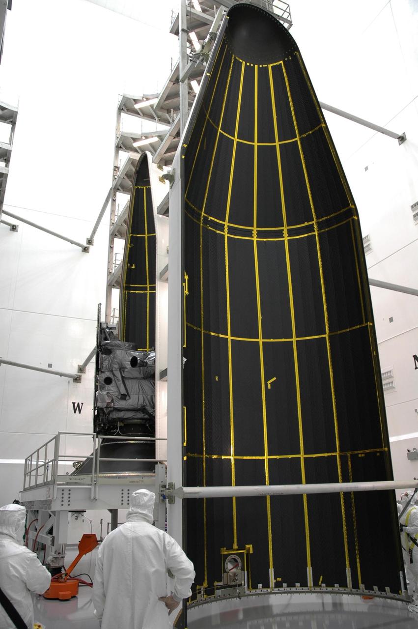 KENNEDY SPACE CENTER, FLA. - At Astrotech Space Operations payload processing facility in Titusville, Fla., the first half of the fairing (right) is moved away from the GOES-N spacecraft after being detached. The spacecraft and second half of the fairing are seen behind it. Workers are using the stand to detach the fairing from around the spacecraft. Workers will use the stand to begin detaching the fairing from around the spacecraft. The fairing protects the spacecraft during launch and flight through the atmosphere. Once out of the atmosphere, the fairing is jettisoned. Removing the fairing will allow workers access to the spacecraft. GOES-N was demated from its Boeing Delta IV launch vehicle when the launch was postponed in August 2005 due to technical issues. Due to the extended length of time the spacecraft had been atop the Delta IV rocket without launching, the weather satellite was returned to Astrotech for some precautionary retesting and state of health checks. GOES-N is the latest in a series of Geostationary Operational Environmental Satellites for NOAA and NASA providing continuous monitoring necessary for intensive data analysis. Photo credit: NASA/Jim Grossmann