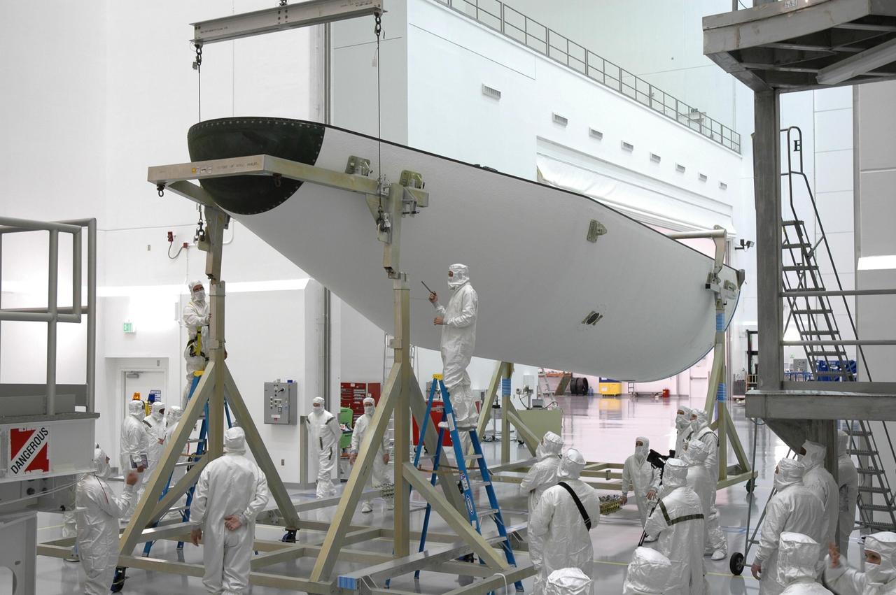 KENNEDY SPACE CENTER, FLA. - At Astrotech Space Operations payload processing facility in Titusville, Fla., workers secure one of the fairing halves removed from around the GOES-N spacecraft onto a horizontal stand. Workers are using the stand to detach the fairing from around the spacecraft. Workers will use the stand to begin detaching the fairing from around the spacecraft. The fairing protects the spacecraft during launch and flight through the atmosphere. Once out of the atmosphere, the fairing is jettisoned. Removing the fairing will allow workers access to the spacecraft. GOES-N was demated from its Boeing Delta IV launch vehicle when the launch was postponed in August 2005 due to technical issues. Due to the extended length of time the spacecraft had been atop the Delta IV rocket without launching, the weather satellite was returned to Astrotech for some precautionary retesting and state of health checks. GOES-N is the latest in a series of Geostationary Operational Environmental Satellites for NOAA and NASA providing continuous monitoring necessary for intensive data analysis. Photo credit: NASA/Jim Grossmann