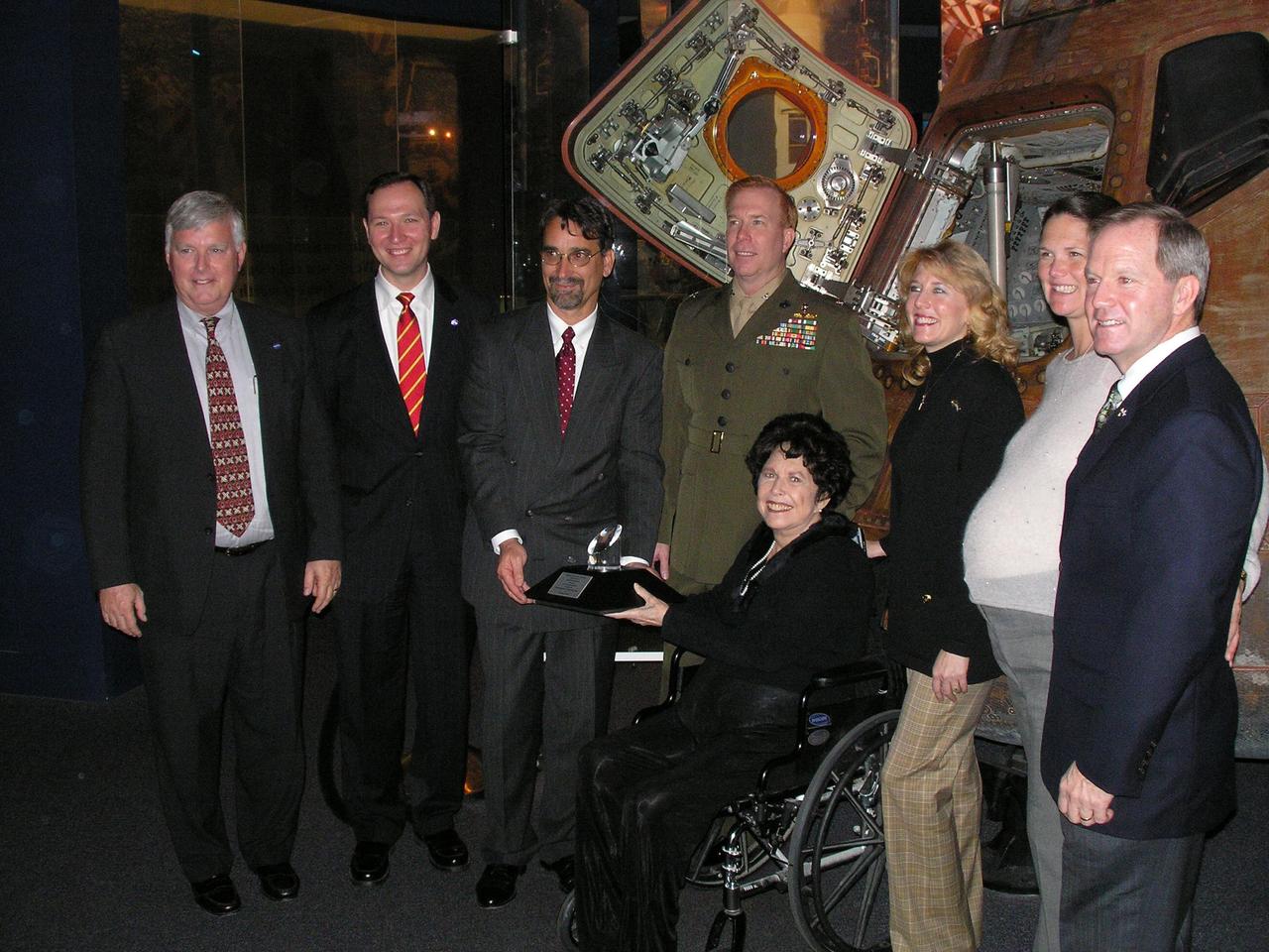 KENNEDY SPACE CENTER, FLA. -  Apollo 14 astronaut Stuart Roosa's family recently was presented with the NASA Ambassador of Exploration Award, recognizing the sacrifices and dedication of the Apollo, Gemini and Mercury astronauts. Attending the ceremony, seen here (from left), are James Kennedy, director, NASA Kennedy Space Center; Jeffrey Jezierski (J. T.), White House liaison, NASA; Daniel Gruenbaum, general manager of the U.S. Astronaut Hall of Fame; and Roosa's family, his son Col. Christopher Roosa, USMC; his widow Joan Roosa, (in wheelchair); his daughter Rosemary Roosa; and daughter-in-law Whitney and his son Allen Roosa.  Each of the honored astronauts or their surviving families was presented with a lunar sample, part of the 842 pounds of moon rocks and soil returned during the six lunar expeditions from 1969 to 1972.  Roosa's family chose to display the award that featured a small piece of the moon at the U.S. Astronaut Hall of Fame in Titusville, Fla.