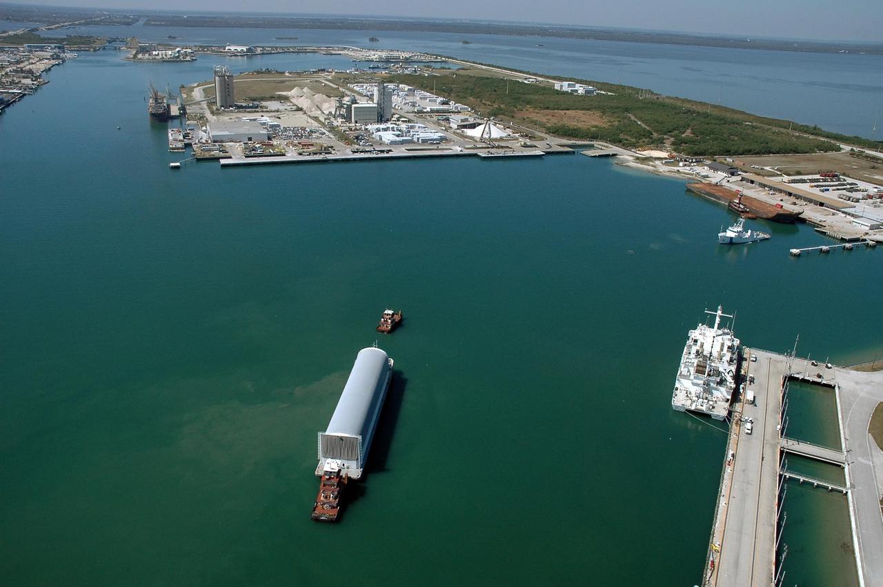 KENNEDY SPACE CENTER, FLA. - The Pegasus barge, towed by the solid rocket booster retrieval ship Freedom Star to Port Canaveral from the Michoud Assembly Facility in New Orleans, waits for a tug boat to finish the trip to the turn basin near NASA Kennedy Space Center's Vehicle Assembly Building. The barge carries the redesigned external fuel tank that will launch the Space Shuttle Discovery on the next shuttle mission, STS-121. After off-loading, the tank will be moved into the Vehicle Assembly Building and lifted into a checkout cell for further work. The tank, designated ET-119, will fly with many major safety changes, including the removal of the protuberance air load ramps. A large piece of foam from one of the ramps came off during the July 2005 launch of the last shuttle mission. The ramps were removed to help eliminate a potential source of damaging debris to the space shuttle. Launch of Discovery is scheduled for May 2006. Photo credit: NASA/Cory Huston
