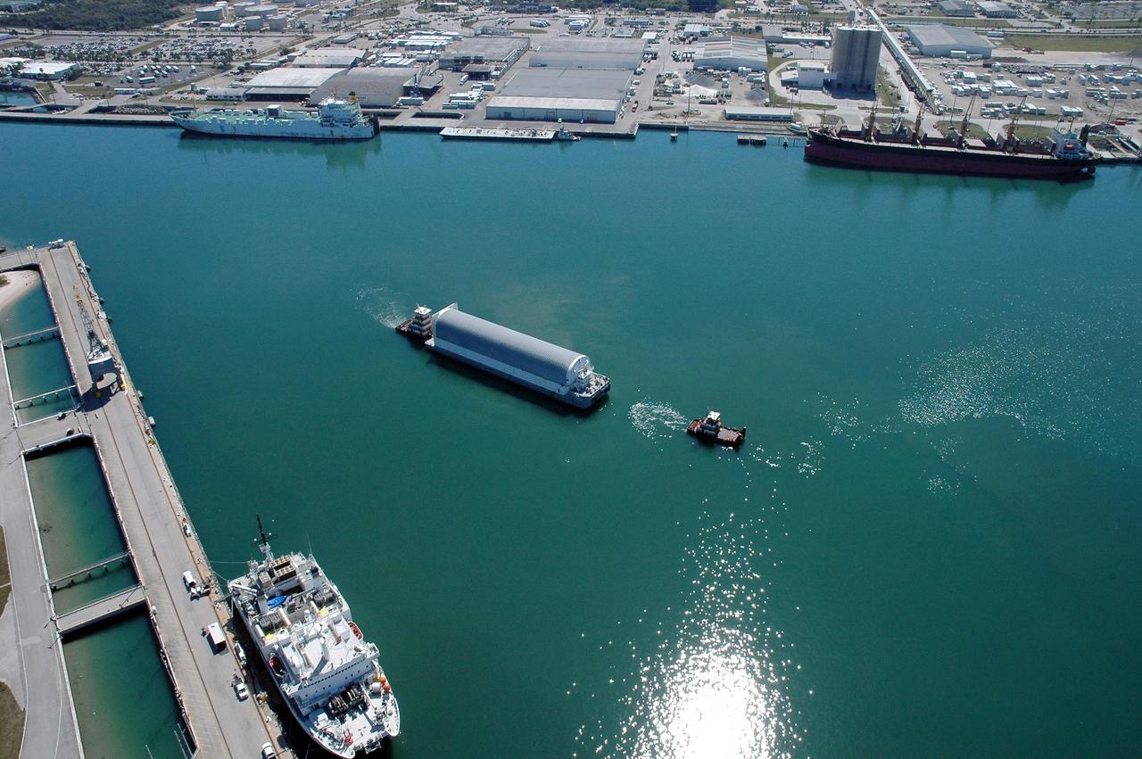 KENNEDY SPACE CENTER, FLA. - The Pegasus barge, towed by the solid rocket booster retrieval ship Freedom Star to Port Canaveral from the Michoud Assembly Facility in New Orleans, waits for a tug boat to finish the trip to the turn basin near NASA Kennedy Space Center's Vehicle Assembly Building. The barge carries the redesigned external fuel tank that will launch the Space Shuttle Discovery on the next shuttle mission, STS-121. After off-loading, the tank will be moved into the Vehicle Assembly Building and lifted into a checkout cell for further work. The tank, designated ET-119, will fly with many major safety changes, including the removal of the protuberance air load ramps. A large piece of foam from one of the ramps came off during the July 2005 launch of the last shuttle mission. The ramps were removed to help eliminate a potential source of damaging debris to the space shuttle. Launch of Discovery is scheduled for May 2006. Photo credit: NASA/Cory Huston