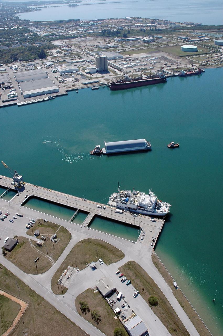 KENNEDY SPACE CENTER, FLA. - The Pegasus barge, towed by the solid rocket booster retrieval ship Freedom Star to Port Canaveral from the Michoud Assembly Facility in New Orleans, waits for a tug boat to finish the trip to the turn basin near NASA Kennedy Space Center's Vehicle Assembly Building. The barge carries the redesigned external fuel tank that will launch the Space Shuttle Discovery on the next shuttle mission, STS-121. After off-loading, the tank will be moved into the Vehicle Assembly Building and lifted into a checkout cell for further work. The tank, designated ET-119, will fly with many major safety changes, including the removal of the protuberance air load ramps. A large piece of foam from one of the ramps came off during the July 2005 launch of the last shuttle mission. The ramps were removed to help eliminate a potential source of damaging debris to the space shuttle. Launch of Discovery is scheduled for May 2006. Photo credit: NASA/Cory Huston