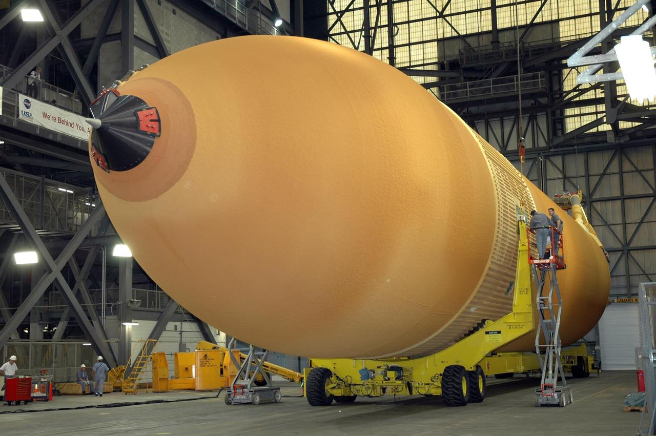 KENNEDY SPACE CENTER, FLA.  -  In NASA Kennedy Space Center's Vehicle Assembly Building, workers are attaching a crane to the newly delivered external tank, which is resting on a transporter in the transfer aisle.  Designated ET-119, the 154-foot tank will be raised to vertical and lifted into a checkout cell for further work.  The tank, which will launch space shuttle Discovery on mission STS-121, will fly with many major safety changes, including the removal of the protuberance air load ramps. A large piece of foam from a ramp came off during the last shuttle launch in July 2005. The ramps were removed to eliminate a potential source of damaging debris to the space shuttle. The next launch of Discovery is scheduled for May 2006. Photo credit: NASA/Jim Grossmann