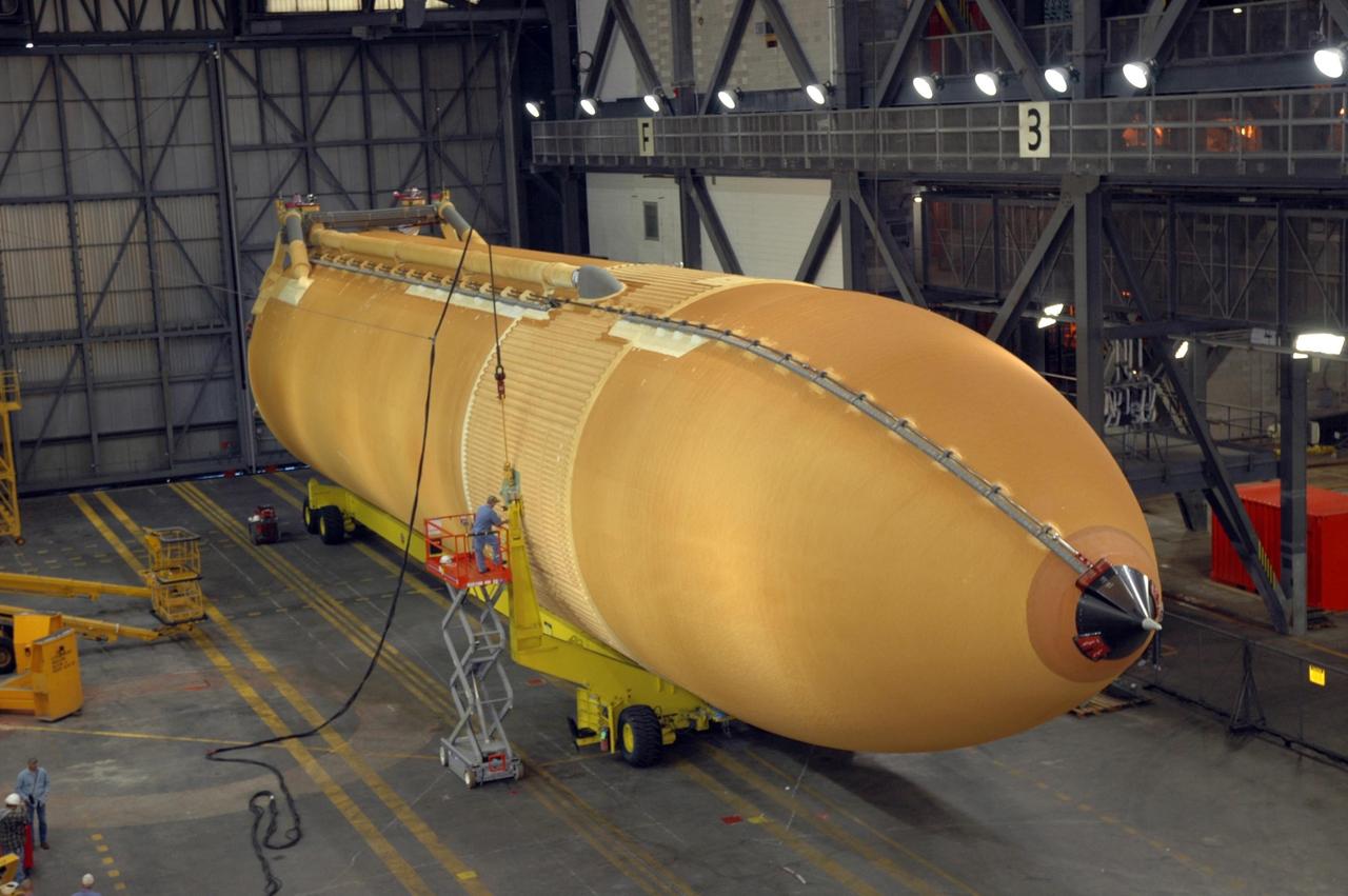 KENNEDY SPACE CENTER, FLA.  -  In NASA Kennedy Space Center's Vehicle Assembly Building, workers are attaching a crane to the newly delivered external tank, which is resting on a transporter in the transfer aisle.  Designated ET-119, the 154-foot tank will be raised to vertical and lifted into a checkout cell for further work.  The tank, which will launch space shuttle Discovery on mission STS-121, will fly with many major safety changes, including the removal of the protuberance air load ramps. A large piece of foam from a ramp came off during the last shuttle launch in July 2005. The ramps were removed to eliminate a potential source of damaging debris to the space shuttle. The next launch of Discovery is scheduled for May 2006. Photo credit: NASA/Jim Grossmann