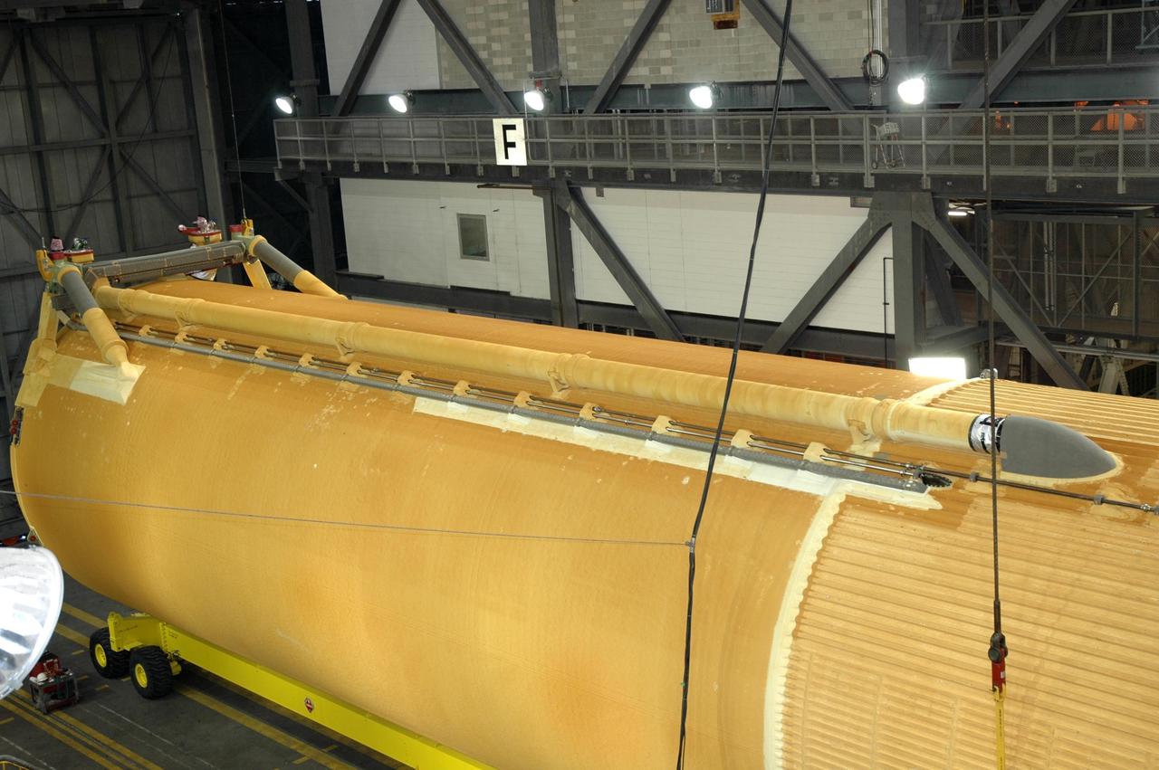 KENNEDY SPACE CENTER, FLA. - In NASA Kennedy Space Center's Vehicle Assembly Building, a crane has been attached to the newly delivered external tank, which is resting on a transporter in the transfer aisle. Designated ET-119, the 154-foot tank will be raised to vertical and lifted into a checkout cell for further work. The tank, which will launch space shuttle Discovery on mission STS-121, will fly with many major safety changes, including the removal of the protuberance air load ramps. A large piece of foam from a ramp came off during the last shuttle launch in July 2005. The ramps were removed to eliminate a potential source of damaging debris to the space shuttle. The next launch of Discovery is scheduled for May 2006. Photo credit: NASA/Jim Grossmann