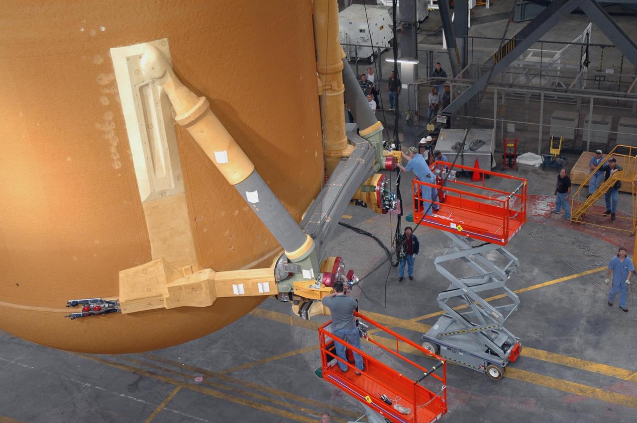 KENNEDY SPACE CENTER, FLA. - In NASA Kennedy Space Center's Vehicle Assembly Building, workers attach another crane to the newly delivered external tank in order to lift it up vertically and over a crossbeam into a checkout cell for further work. Designated ET-119, the 154-foot tank will be lifted into a checkout cell for further work. The tank, which will launch space shuttle Discovery on mission STS-121, will fly with many major safety changes, including the removal of the protuberance air load ramps. A large piece of foam from a ramp came off during the last shuttle launch in July 2005. The ramps were removed to eliminate a potential source of damaging debris to the space shuttle. The next launch of Discovery is scheduled for May 2006. Photo credit: NASA/Jim Grossmann