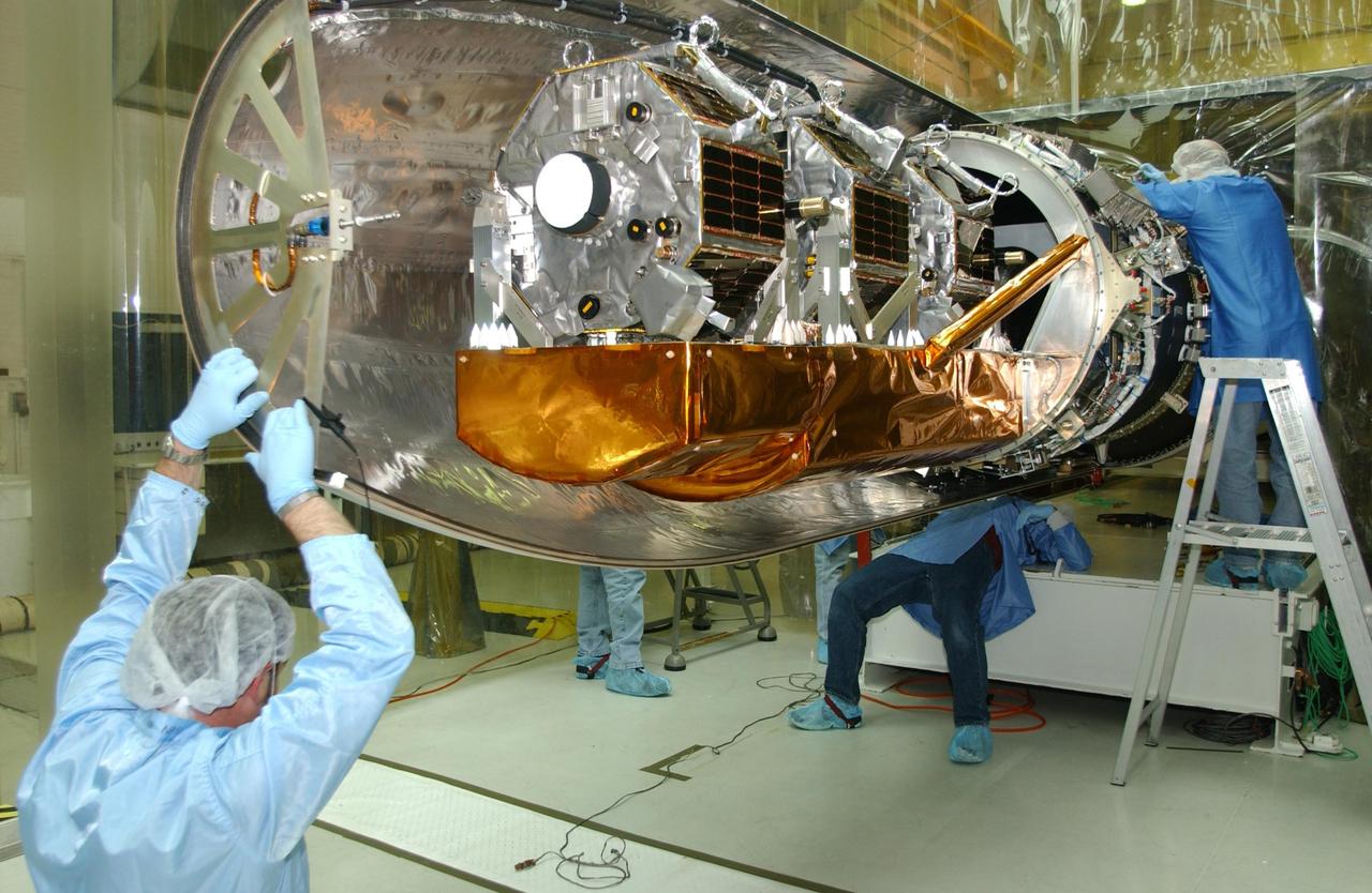VANDENBERG AIR FORCE BASE, CALIF. - Inside Orbital Sciences’ Building 1555 at Vandenberg Air Force Base in California, workers adjust the first half of the fairing being installed around the Space Technology 5 (ST5) spacecraft.  The ST5 contains three microsatellites with miniaturized redundant components and technologies.  Each will validate New Millennium Program selected technologies, such as the Cold Gas Micro-Thruster and X-Band Transponder Communication System.  After deployment from the Pegasus, the micro-satellites will be positioned in a “string of pearls” constellation that demonstrates the ability to position them to perform simultaneous multi-point measurements of the magnetic field using highly sensitive magnetometers.  The data will help scientists understand and map the intensity and direction of the Earth’s magnetic field, its relation to space weather events, and affects on our planet.  With such missions, NASA hopes to improve scientists’ ability to accurately forecast space weather and minimize its harmful effects on space- and ground-based systems.  Launch of ST5 is scheduled from the belly of an L-1011 carrier aircraft no earlier than March 14 from Vandenberg Air Force Base.