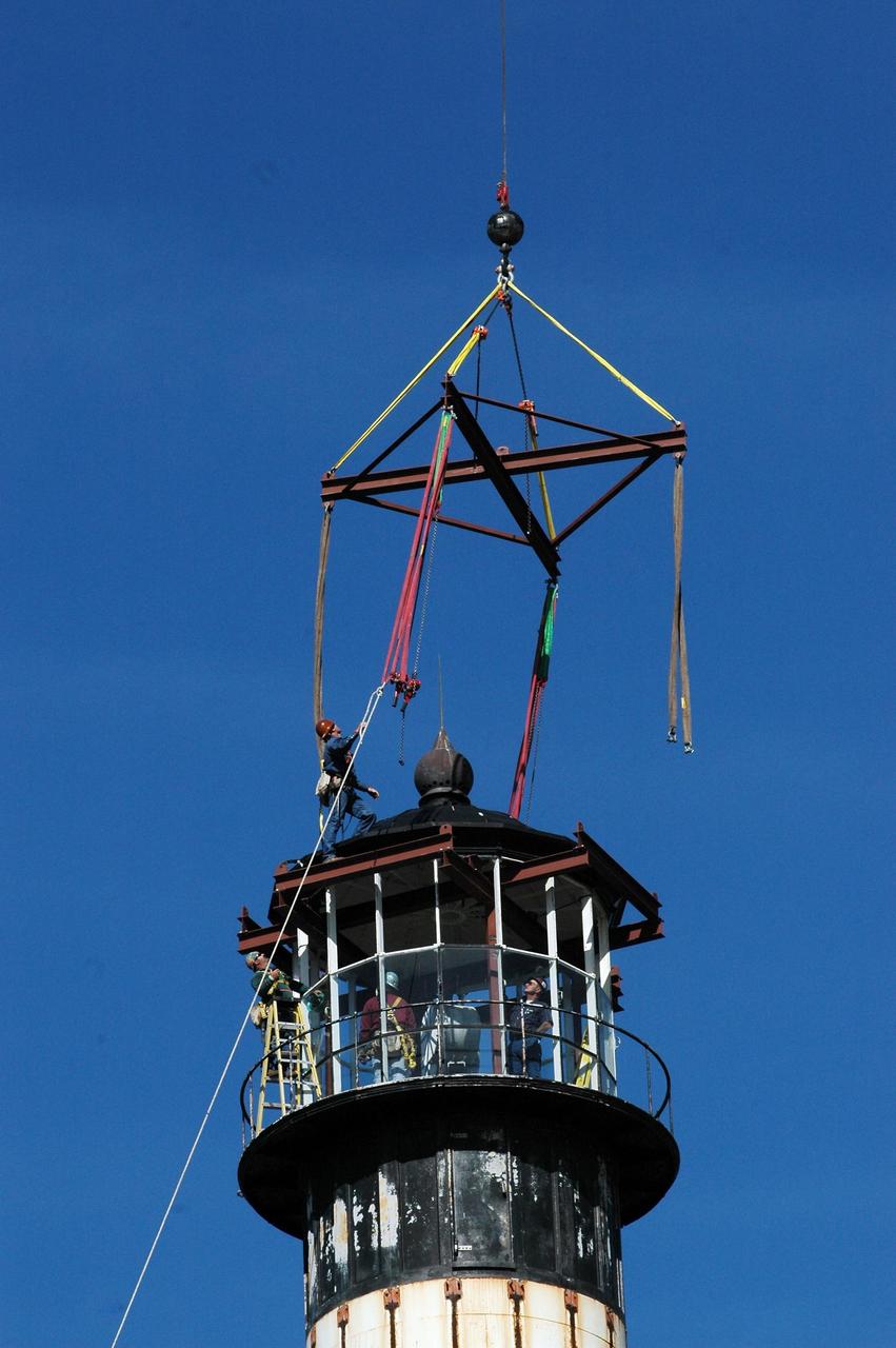 KENNEDY SPACE CENTER, FLA.  - At Cape Canaveral Air Force Station, workers get ready to attach a crane to the top of the lamp room on the Cape Canaveral Lighthouse. Leaks in the roof allowed moisture to seep in.  The lamp room is being removed for repairs and refurbishment.  In addition, the original brass roof will be restored and put back in place. The Cape Canaveral Lighthouse is the only operational lighthouse owned by the Air Force. It was first erected in 1868 near the edge of the Atlantic Ocean.  Photo credit: NASA/Jack Pfaller