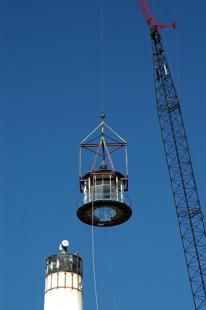 KENNEDY SPACE CENTER, FLA. - At Cape Canaveral Air Force Station, a crane swings the detached lamp room clear of the beacon on the Cape Canaveral Lighthouse. Leaks in the roof allowed moisture to seep in. The lamp room is being removed for repairs and refurbishment. In addition, the original brass roof will be restored and put back in place. The Cape Canaveral Lighthouse is the only operational lighthouse owned by the Air Force. It was first erected in 1868 near the edge of the Atlantic Ocean. Photo credit: NASA/Jack Pfaller
