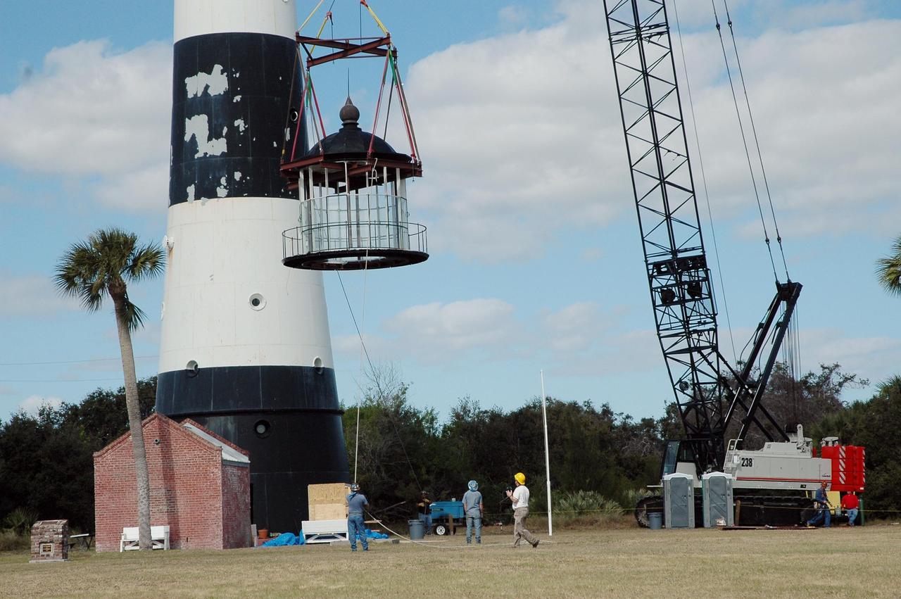 KENNEDY SPACE CENTER, FLA.  - At Cape Canaveral Air Force Station,  workers below help guide the detached lamp room from the Cape Canaveral Lighthouse onto the ground.  Leaks in the roof allowed moisture to seep in.   The lamp room is being removed for repairs and refurbishment.  In addition, the original brass roof will be restored and put back in place. The Cape Canaveral Lighthouse is the only operational lighthouse owned by the Air Force. It was first erected in 1868 near the edge of the Atlantic Ocean.  Photo credit: NASA/Jack Pfaller