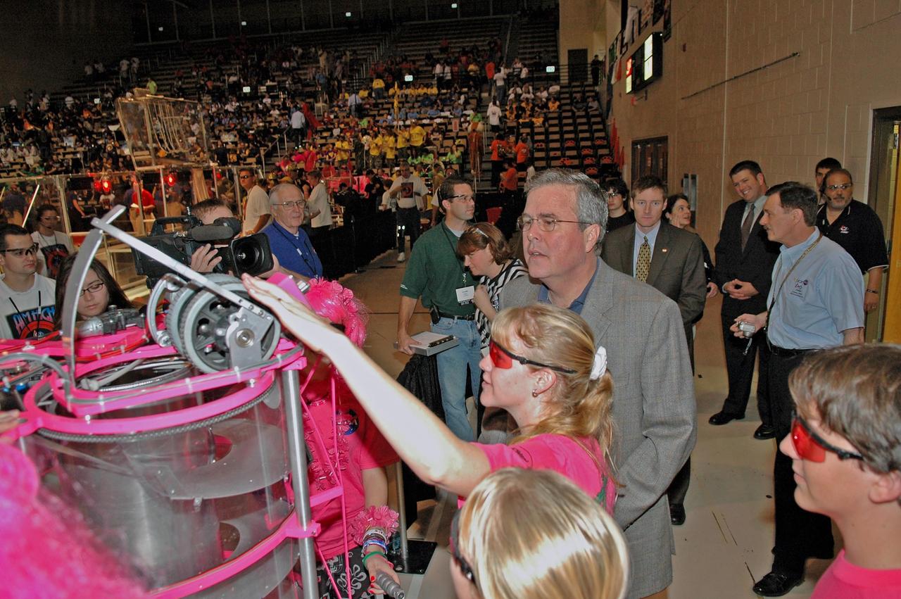 KENNEDY SPACE CENTER, FLA. - Members of the "Pink Team" explain their robot to Florida Governor Jeb Bush at the 2006 FIRST Robotics Regional Competition held March 9-11 at the University of Central Florida in Orlando. The Pink Team, whose robot is named Roccobot, is co-sponsored by NASA KSC. At least four teams in the competition were sponsored by KSC, NASA and contractors. The FIRST Robotics Competition challenges teams of young people and their mentors to solve a common problem in a six-week timeframe using a standard "kit of parts" and a common set of rules. Teams build robots from the parts and enter them in a series of competitions. FIRST, which is based on "For Inspiration and Recognition of Science and Technology," redefines winning for these students. Teams are rewarded for excellence in design, demonstrated team spirit, gracious professionalism and maturity, and ability to overcome obstacles. Scoring the most points is a secondary goal. Winning means building partnerships that last. NASA and the University of Central Florida are co-sponsors of the regional event, which this year included more than 50 teams. Photo credit: NASA/Kim Shiflett