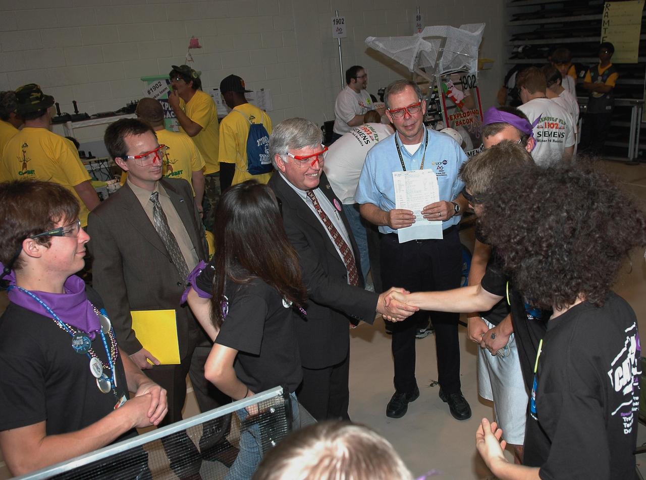 KENNEDY SPACE CENTER, FLA.  -  During the 2006 FIRST Robotics Regional Competition held March 9-11 at the University of Central Florida in Orlando, Kennedy Space Center Director Jim Kennedy greets members of one of the robotic teams.  To the left of Kennedy is Neil Berger, the center director's intern; at right of Kennedy is Chris Fairey, retired NASA and Regional Planning Committee co-chair.  The FIRST  Robotics Competition challenges teams of young people and their mentors to solve a common problem in a six-week timeframe using a standard "kit of parts" and a common set of rules. Teams build robots from the parts and enter them in a series of competitions.  FIRST, which is based on "For Inspiration and Recognition of Science and Technology," redefines winning for these students. Teams are rewarded for excellence in design, demonstrated team spirit, gracious professionalism and maturity, and ability to overcome obstacles. Scoring the most points is a secondary goal. Winning means building partnerships that last.  NASA and the University of Central Florida are co-sponsors of the regional event, which this year included more than 50 teams.  Photo credit: NASA/Kim Shiflett