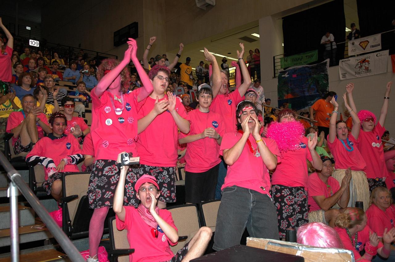 KENNEDY SPACE CENTER, FLA. - Members of the "Pink Team" cheer on their robot, Roccobot, during matches at the 2006 FIRST Robotics Regional Competition held March 9-11 at the University of Central Florida in Orlando. The Pink Team comprises students from Rockledge High and Cocoa Beach High Schools and is co-sponsored by NASA KSC. The team received the Regional Chairman's Award, described as going to the team judged to have created the best partnership effort among team participants and to have best exemplified the true meaning of FIRST. The FIRST Robotics Competition challenges teams of young people and their mentors to solve a common problem in a six-week timeframe using a standard "kit of parts" and a common set of rules. Teams build robots from the parts and enter them in a series of competitions. FIRST, which is based on "For Inspiration and Recognition of Science and Technology," redefines winning for these students. Teams are rewarded for excellence in design, demonstrated team spirit, gracious professionalism and maturity, and ability to overcome obstacles. Scoring the most points is a secondary goal. Winning means building partnerships that last. NASA and the University of Central Florida are co-sponsors of the regional event, which this year included more than 50 teams. Photo credit: NASA/Kim Shiflett