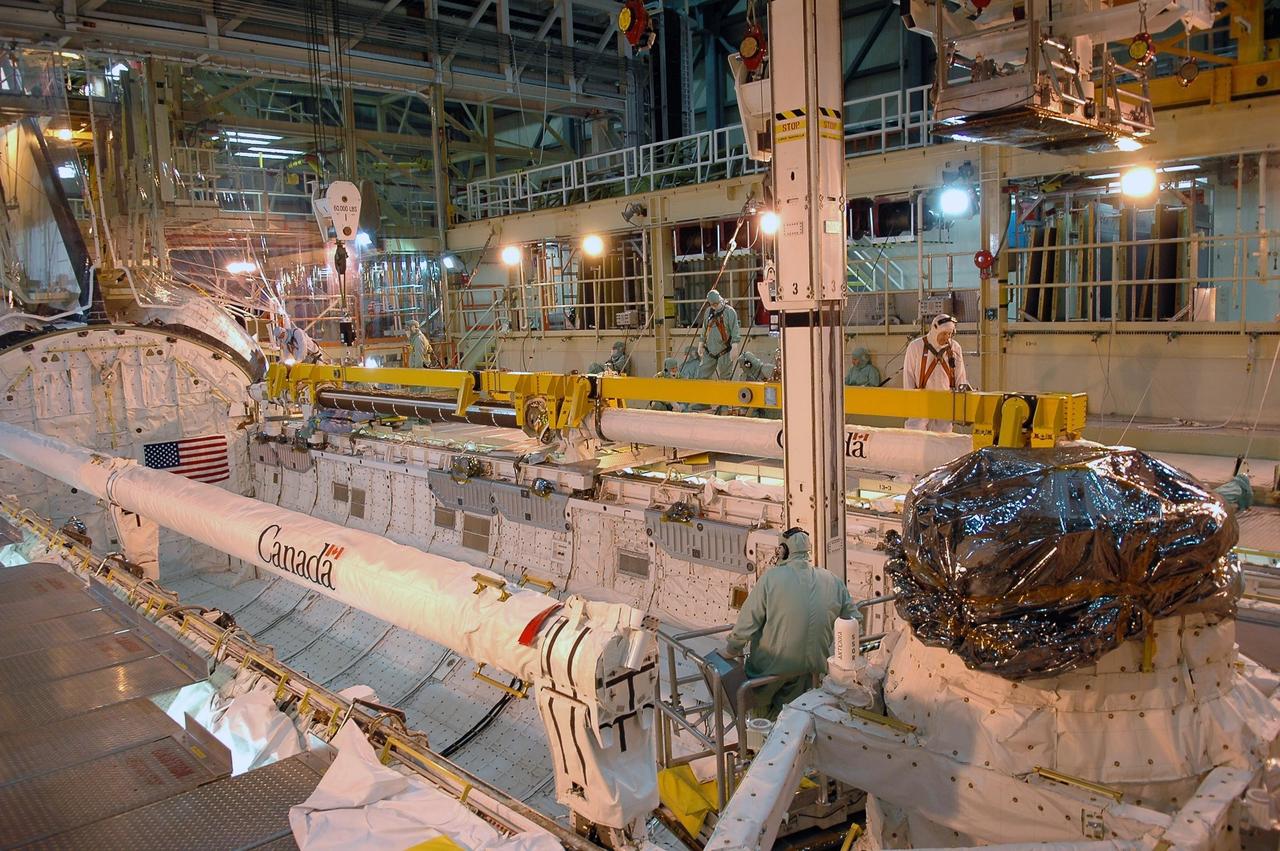 KENNEDY SPACE CENTER, FLA.  -   Inside the Orbiter Processing Facility bay 3 at NASA's Kennedy Space Center, workers attach an overhead crane to Discovery's robotic arm in the payload bay. The arm is being removed due to damage found on the arm after it was accidentally bumped by a bridge bucket in the payload bay.  Ultrasound inspections revealed a small crack, measuring 1.25 inches by 0.015 inch deep.  The arm will be sent back to the vendor for repair.  The bucket was being used by technicians cleaning the area and was in the process of being stowed.  A bridge bucket is a personnel transport device that is suspended from an overhead bridge that moves back and forth above the shuttle's mid-body. It allows workers to access the payload bay area without walking or standing on the payload bay floor or on the fixed platforms.  Space Shuttle Discovery is scheduled for launch on mission STS-121 during a launch planning window of July 1-19.    Photo credit: NASA/Kim Shiflett