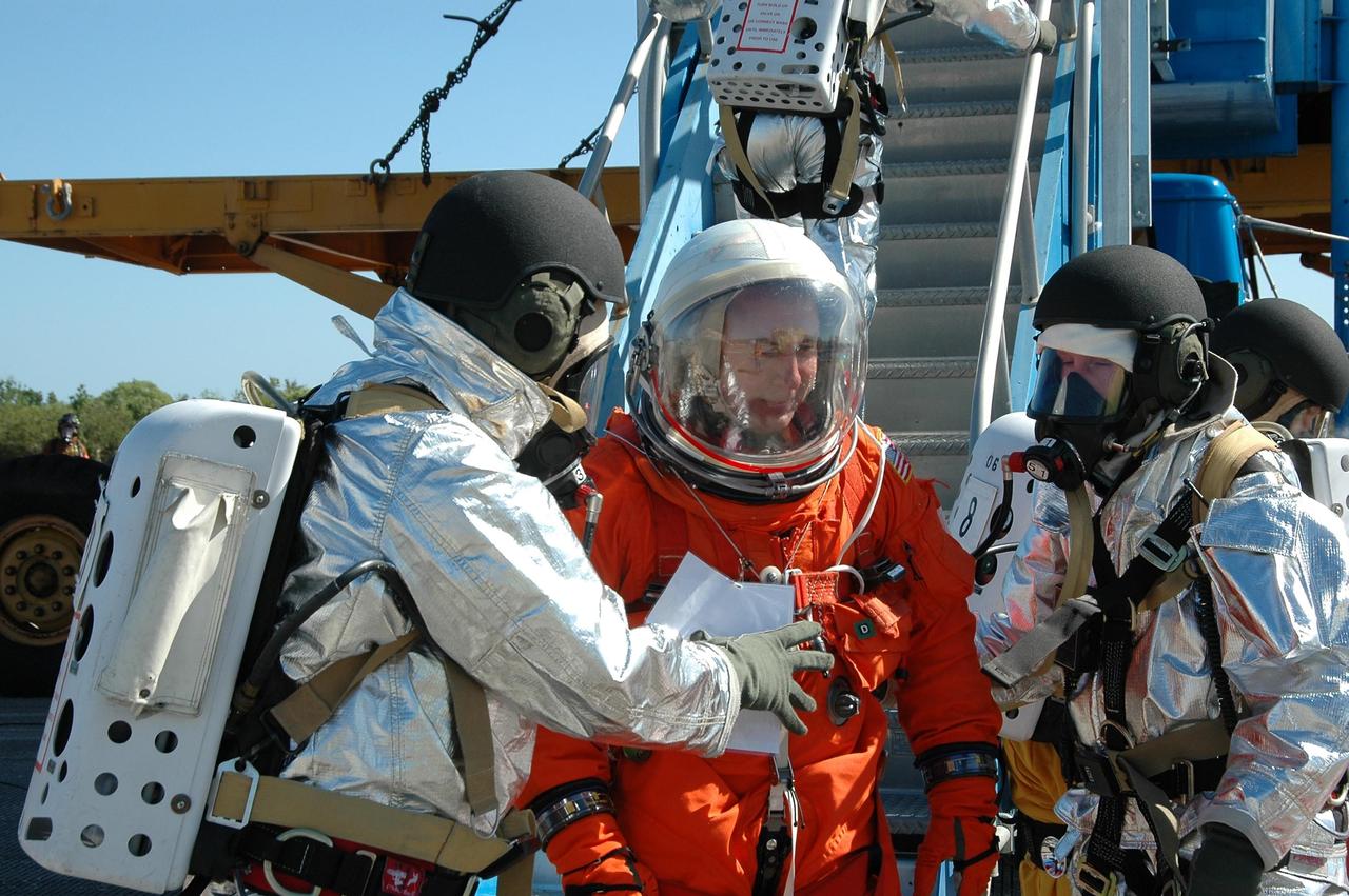 KENNEDY SPACE CENTER, FLA.  -  In a simulated emergency landing of a shuttle crew at NASA Kennedy Space Center's Shuttle Landing Facility, an "astronaut" exits the orbiter mockup.  Emergency rescue personnel are behind.   Known as a Mode VI exercise, the operation uses volunteer workers from the Center to pose as astronauts. The purpose of the simulation is to exercise emergency preparedness personnel, equipment and facilities in rescuing astronauts from a downed orbiter and providing immediate medical attention. Photo credit: NASA/Kim Shiflett