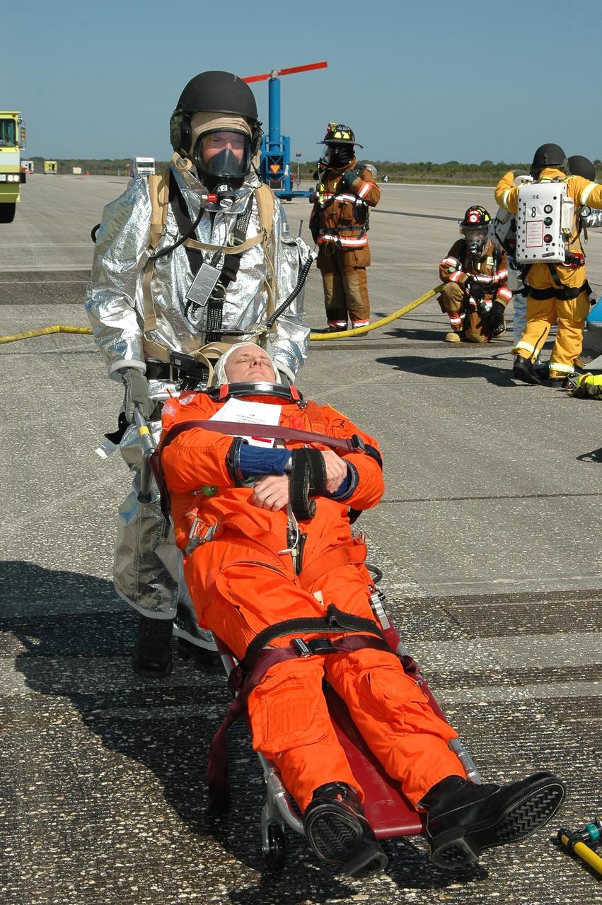 KENNEDY SPACE CENTER, FLA.  -  In a simulated emergency landing of a shuttle crew at NASA Kennedy Space Center's Shuttle Landing Facility, emergency rescue personnel move an "injured astronaut" away from the orbiter mockup.  Known as a Mode VI exercise, the operation uses volunteer workers from the Center to pose as astronauts. The purpose of the simulation is to exercise emergency preparedness personnel, equipment and facilities in rescuing astronauts from a downed orbiter and providing immediate medical attention. Photo credit: NASA/Kim Shiflett