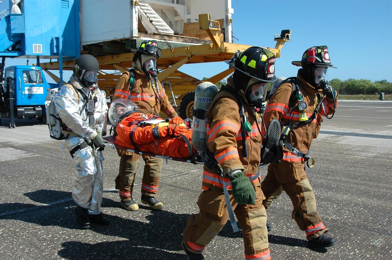 KENNEDY SPACE CENTER, FLA.  -  In a simulated emergency landing of a shuttle crew at NASA Kennedy Space Center's Shuttle Landing Facility, emergency rescue personnel carry an "injured astronaut" away from the orbiter mockup.  Known as a Mode VI exercise, the operation uses volunteer workers from the Center to pose as astronauts. The purpose of the simulation is to exercise emergency preparedness personnel, equipment and facilities in rescuing astronauts from a downed orbiter and providing immediate medical attention. Photo credit: NASA/Kim Shiflett