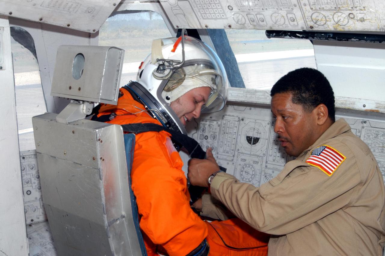 KENNEDY SPACE CENTER, FLA.  -    Inside the orbiter mockup at NASA Kennedy Space Center's Shuttle Landing Facility,  volunteer "astronaut" Jeremy Garcia, with United Space Alliance (USA), is helped with his launch and entry suit by USA Insertion Tech George Brittingham before a simulated emergency landing of a shuttle crew.  Known as a Mode VI exercise, the operation uses volunteer workers from the Center to pose as astronauts. The purpose of the simulation is to exercise emergency preparedness personnel, equipment and facilities in rescuing astronauts from a downed orbiter and providing immediate medical attention. Photo credit: NASA/George Shelton