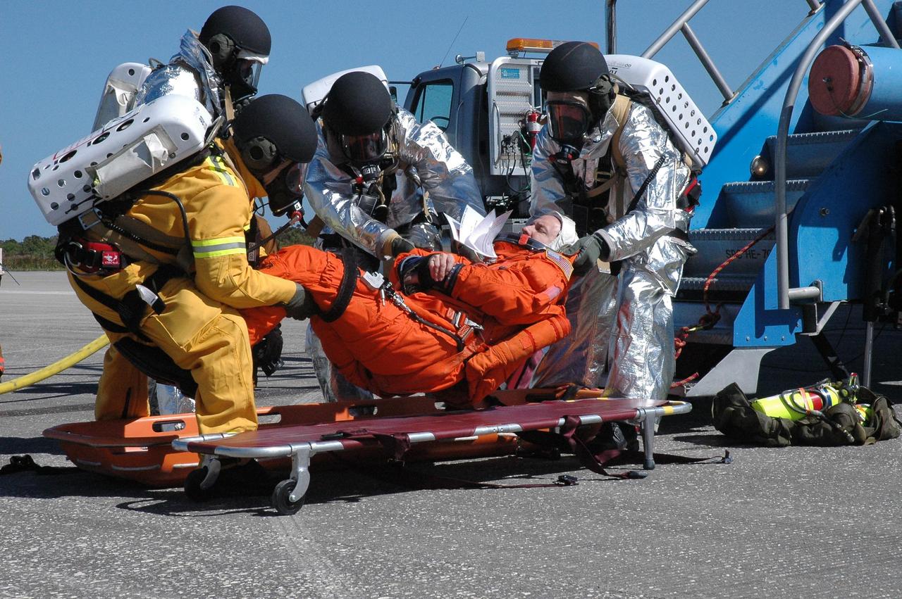KENNEDY SPACE CENTER, FLA.  -  At NASA Kennedy Space Center's Shuttle Landing Facility, emergency rescue personnel gently place an "injured astronaut" onto a stretcher.  Volunteers and emergency rescue workers are participating in a simulated emergency landing of a shuttle crew. Known as a Mode VI exercise, the operation uses volunteer workers from the Center to pose as astronauts. The purpose of the simulation is to exercise emergency preparedness personnel, equipment and facilities in rescuing astronauts from a downed orbiter and providing immediate medical attention. Photo credit: NASA/Troy Cryder