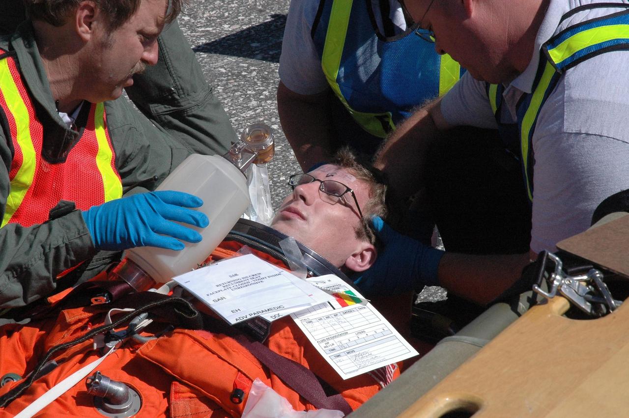 KENNEDY SPACE CENTER, FLA.  -  At NASA Kennedy Space Center's Shuttle Landing Facility, volunteer Charlie Plain poses as an injured astronaut during a simulated emergency landing of a shuttle crew.  Plain is a Public Affairs Web writer.   Known as a Mode VI exercise, the operation uses volunteer workers from the Center to pose as astronauts. The purpose of the simulation is to exercise emergency preparedness personnel, equipment and facilities in rescuing astronauts from a downed orbiter and providing immediate medical attention. Photo credit: NASA/Troy Cryder