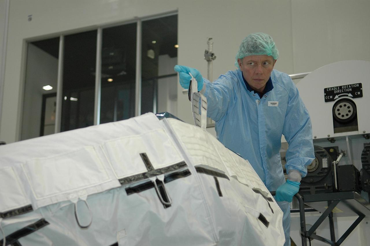 KENNEDY SPACE CENTER, FLA. - During a Crew Equipment Interface Test (CEIT) inside the Space Station Processing Facility at NASA's Kennedy Space Center, STS-121 Mission Specialist Michael Fossum holds a loop on a cover for the trailing umbilical system reel assembly that will be installed on the International Space Station during their mission. A CEIT provides hands-on experiences with equipment used on-orbit. Mission STS-121 is the second in the Return to Flight sequence and will carry on improvements that debuted during last year's STS-114 mission and build upon those tests. Launch is scheduled in July. Photo credit: NASA/Kim Shiflett