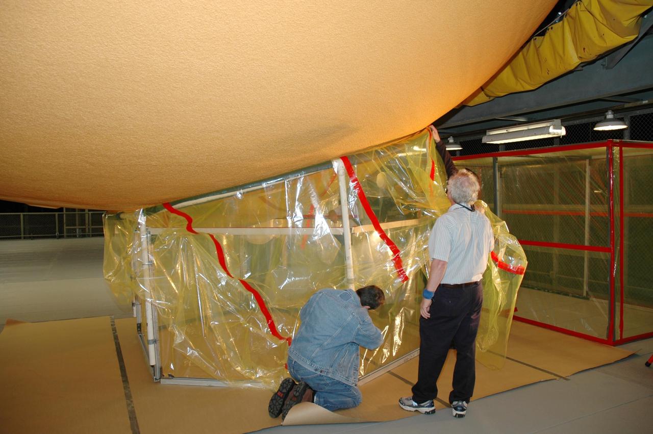KENNEDY SPACE CENTER, FLA. - KENNEDY SPACE CENTER, FLA. - Lockheed Martin technicians from NASA's Michoud Assembly Facility in Louisiana install a clean-room working area around the "manhole" on the external tank designated for mission STS-121. The work is part of the process in removing and replacing the external tank's four liquid hydrogen main engine cutoff sensors, which indicate whether the tank still has fuel during its climb to orbit. After the cleaning, the manhole will be removed to provide access to the area of the sensors for their removal. Photo credit: NASA/Jim Grossmann