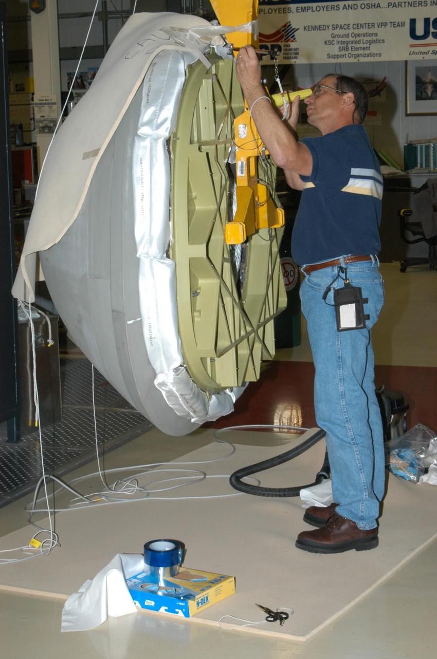KENNEDY SPACE CENTER, FLA. - In Orbiter Processing Facility bay 2 at NASA's Kennedy Space Center, a worker examines the underside of the reinforced carbon-carbon nose cap that will be installed on Endeavour. The nose cap is insulated with thermal protection system blankets made of a woven ceramic fabric. The special blankets help insulate the vehicle's nose cap and protect it from the extreme temperatures it will face during a mission. Photo credit: NASA/George Shelton