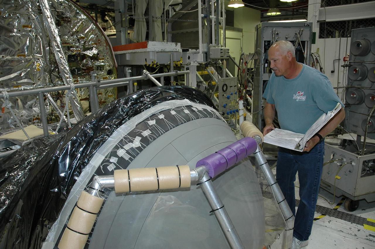 KENNEDY SPACE CENTER, FLA. -  In Orbiter Processing Facility bay 2 at NASA's Kennedy Space Center, a worker checks the reinforced carbon-carbon nose cap after installation on Endeavour.  The nose cap has been insulated with thermal protection system blankets made of a woven ceramic fabric.  The special blankets help insulate the vehicle's nose cap and protect it from the extreme temperatures it will face during a mission. Photo credit: NASA/Jim Grossmann