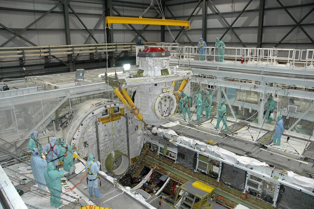 KENNEDY SPACE CENTER, FLA. - In Orbiter Processing Facility bay 2 at NASA's Kennedy Space Center, the airlock is lowered by an overhead crane into Endeavour's payload bay for installation. The airlock is located in the middeck. The airlock and airlock hatches permit flight crew members to transfer from the middeck crew compartment into the payload bay for extravehicular activities in their space suits without depressurizing the orbiter crew cabin. The airlock is sized to accommodate two fully suited flight crew members simultaneously. Photo credit: NASA/Jim Grossmann